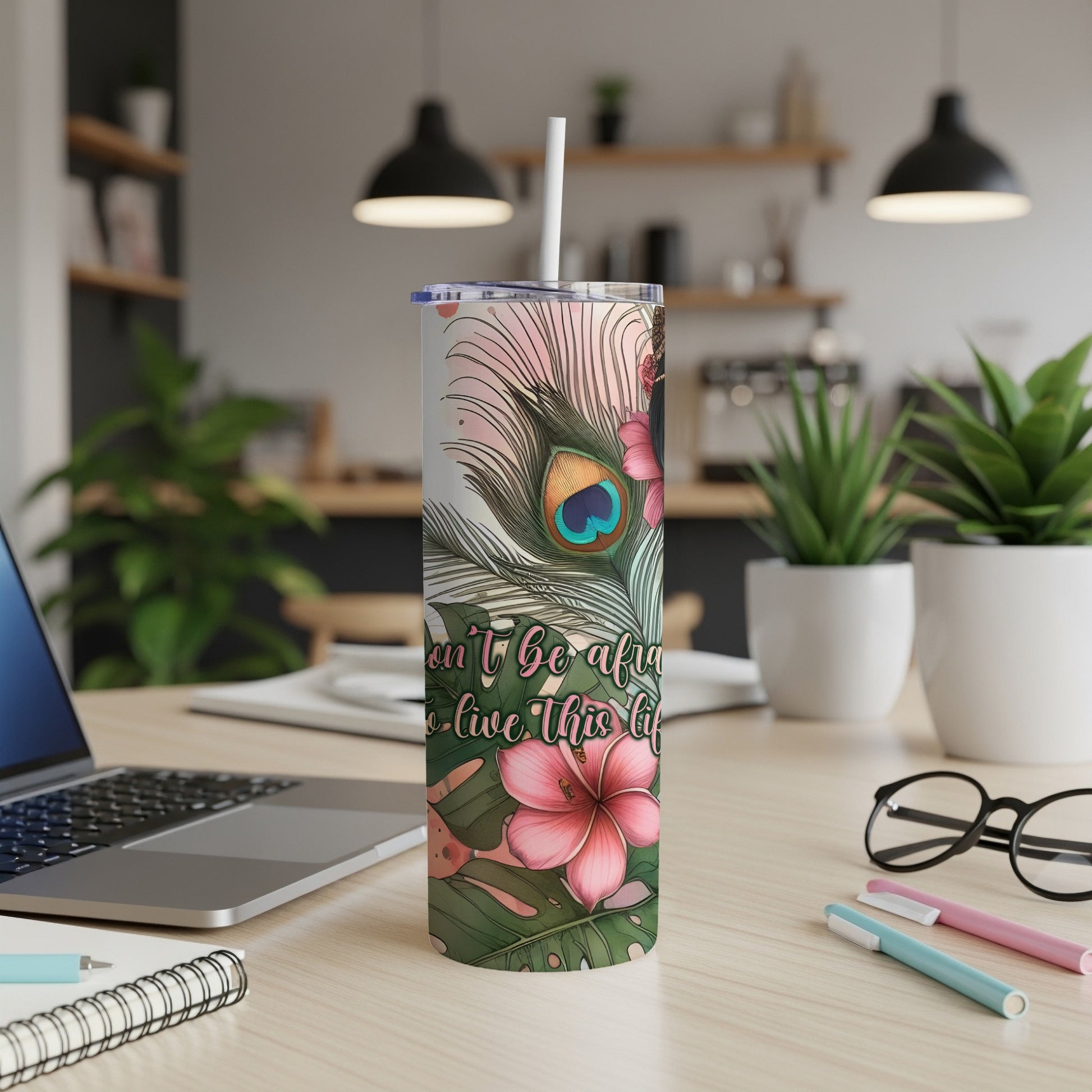 Tall tumbler with a floral and peacock feather design and inspirational text.