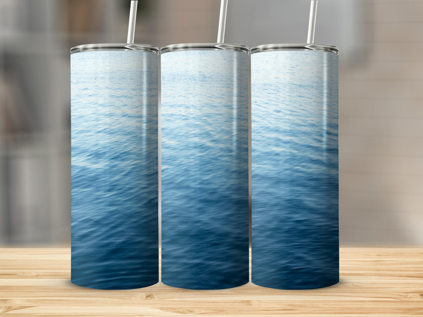 Three tumblers with a blue water surface pattern stand on a wooden surface.