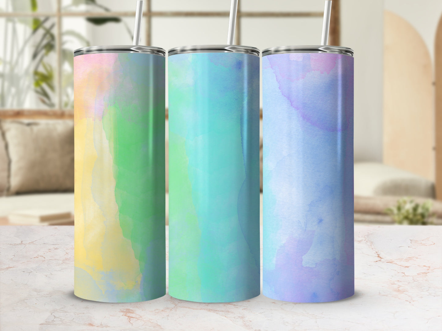 Three tumblers with pastel watercolor designs and straws.