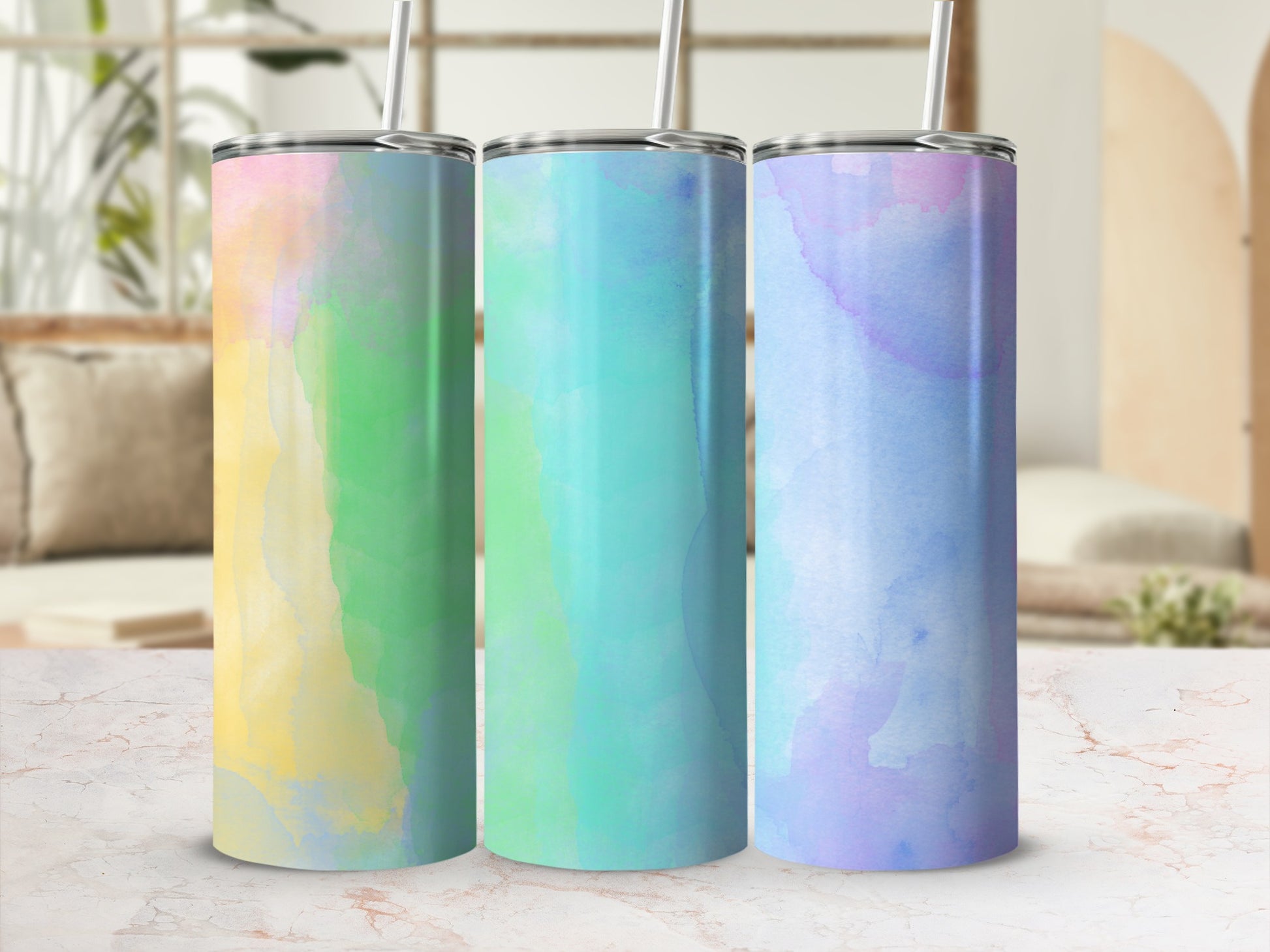 Three tumblers with pastel watercolor designs and straws.