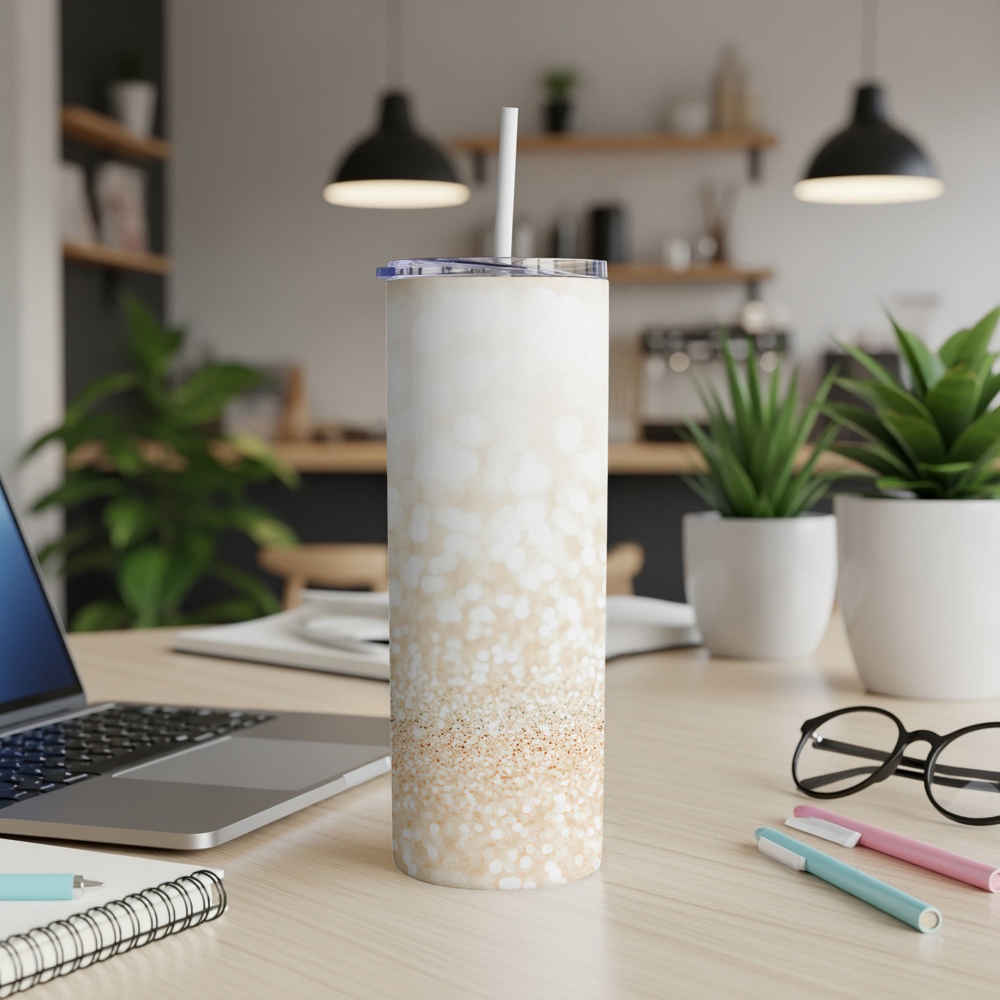 White glitter tumbler with straw on a desk next to a laptop.