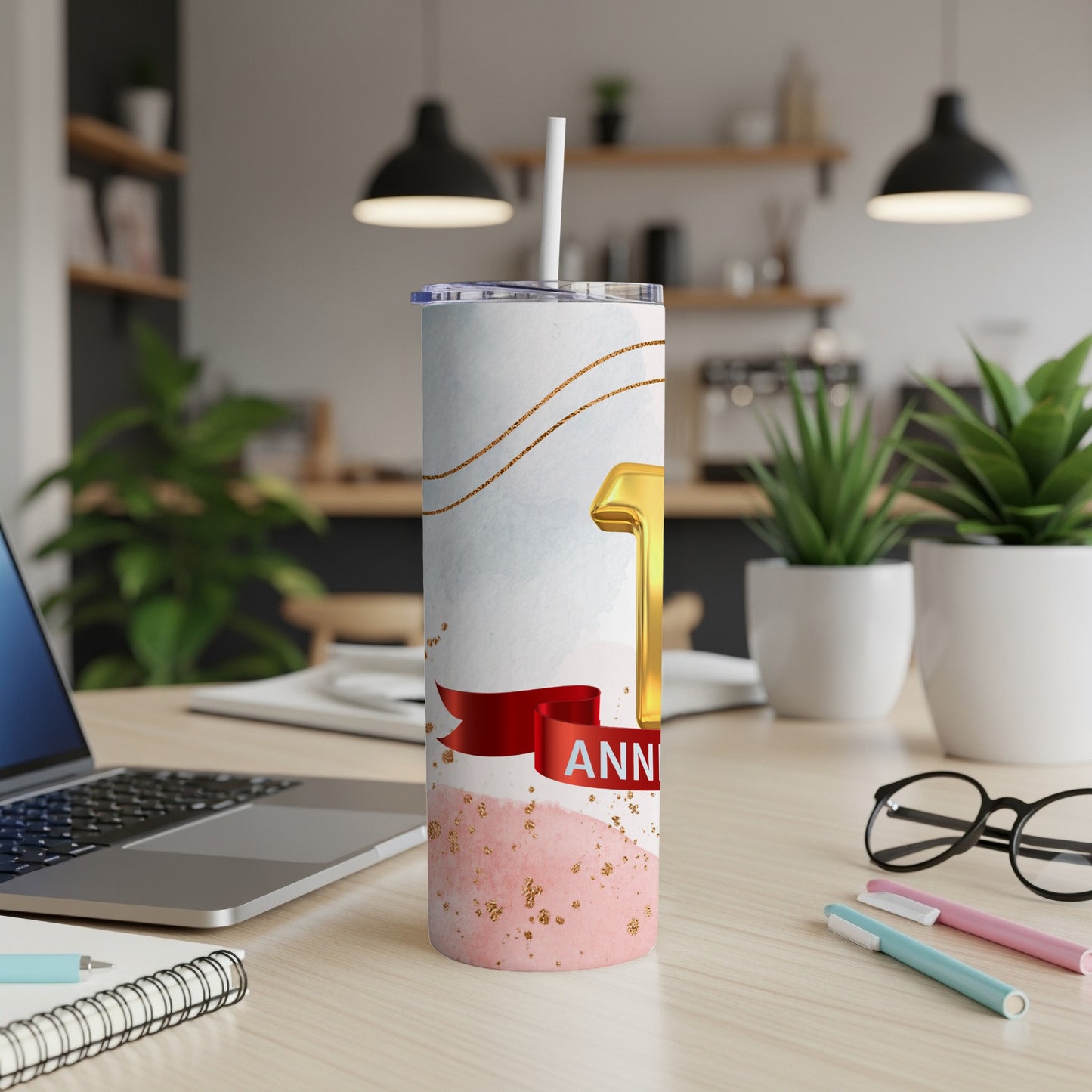 Gold "1st Anniversary" tumbler with red ribbon on a desk.