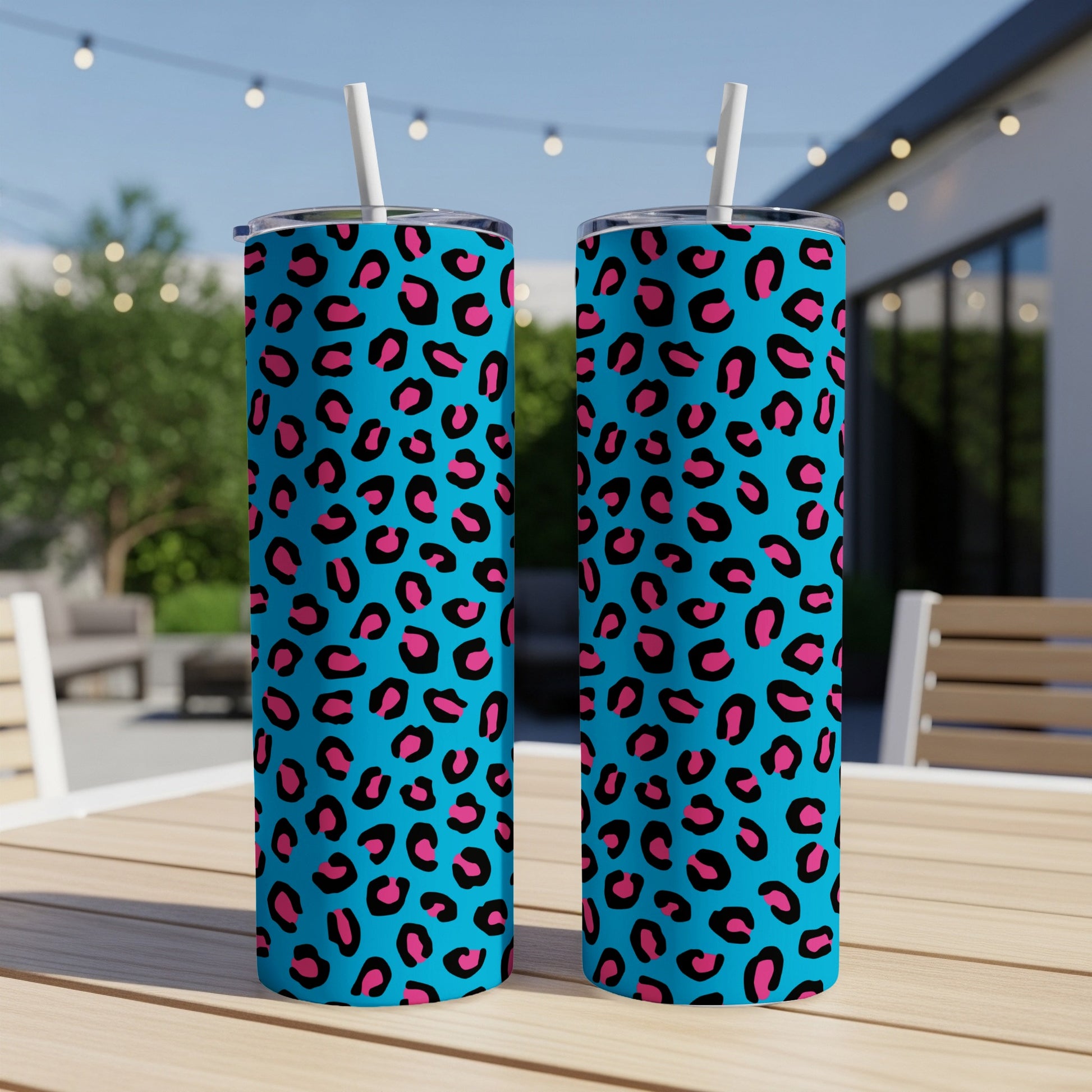Two blue tumblers with pink and black leopard print and white straws.