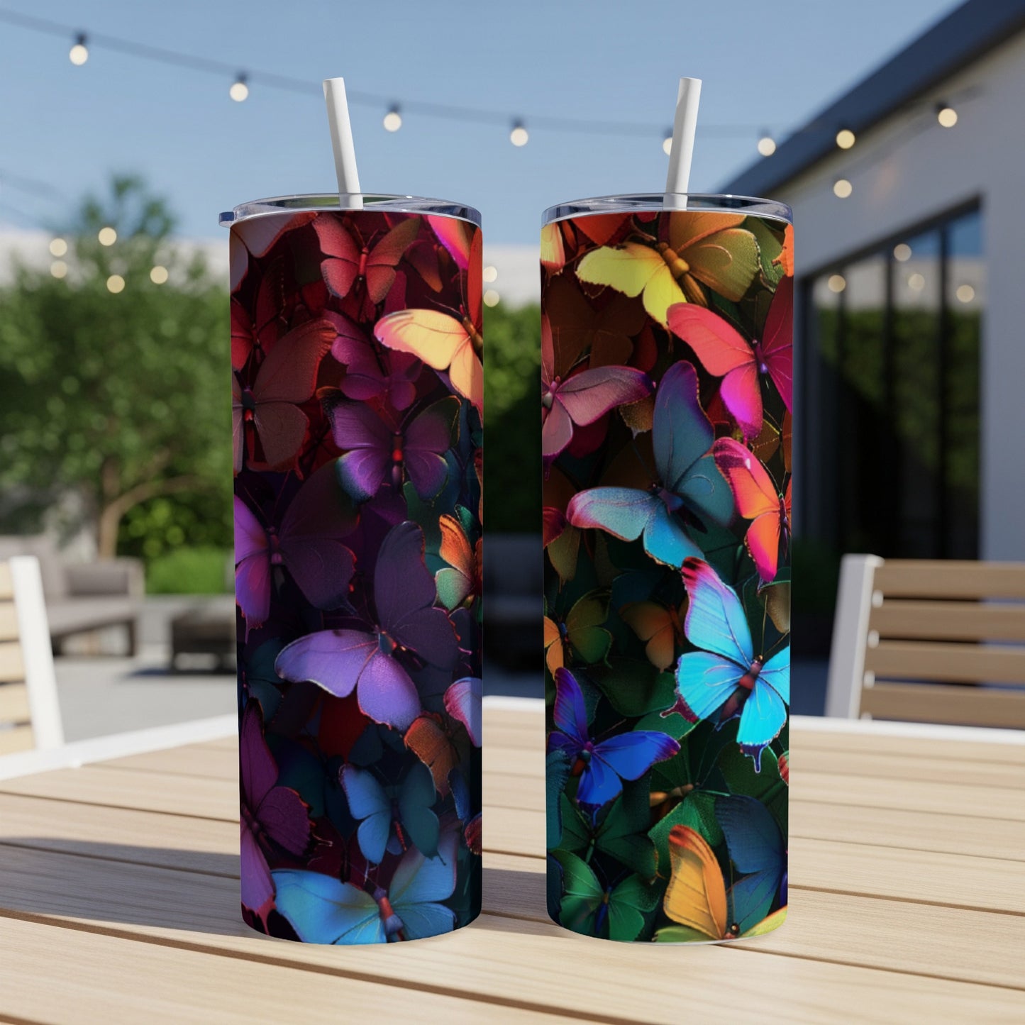 Two tumblers with colorful butterfly designs sit on a table outdoors.