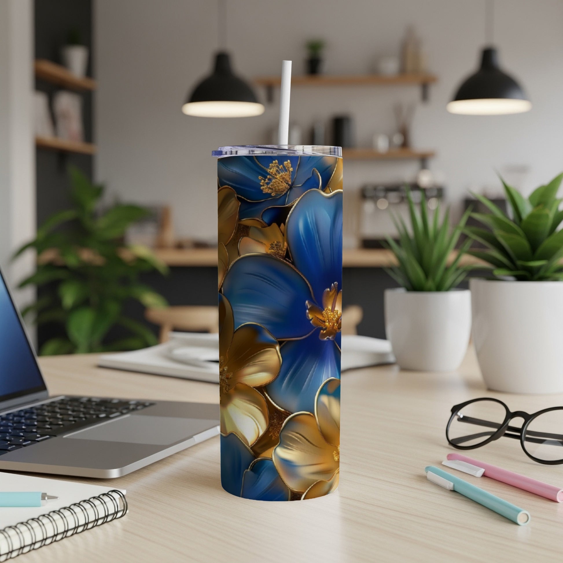 Blue and gold floral tumbler with straw on a desk.