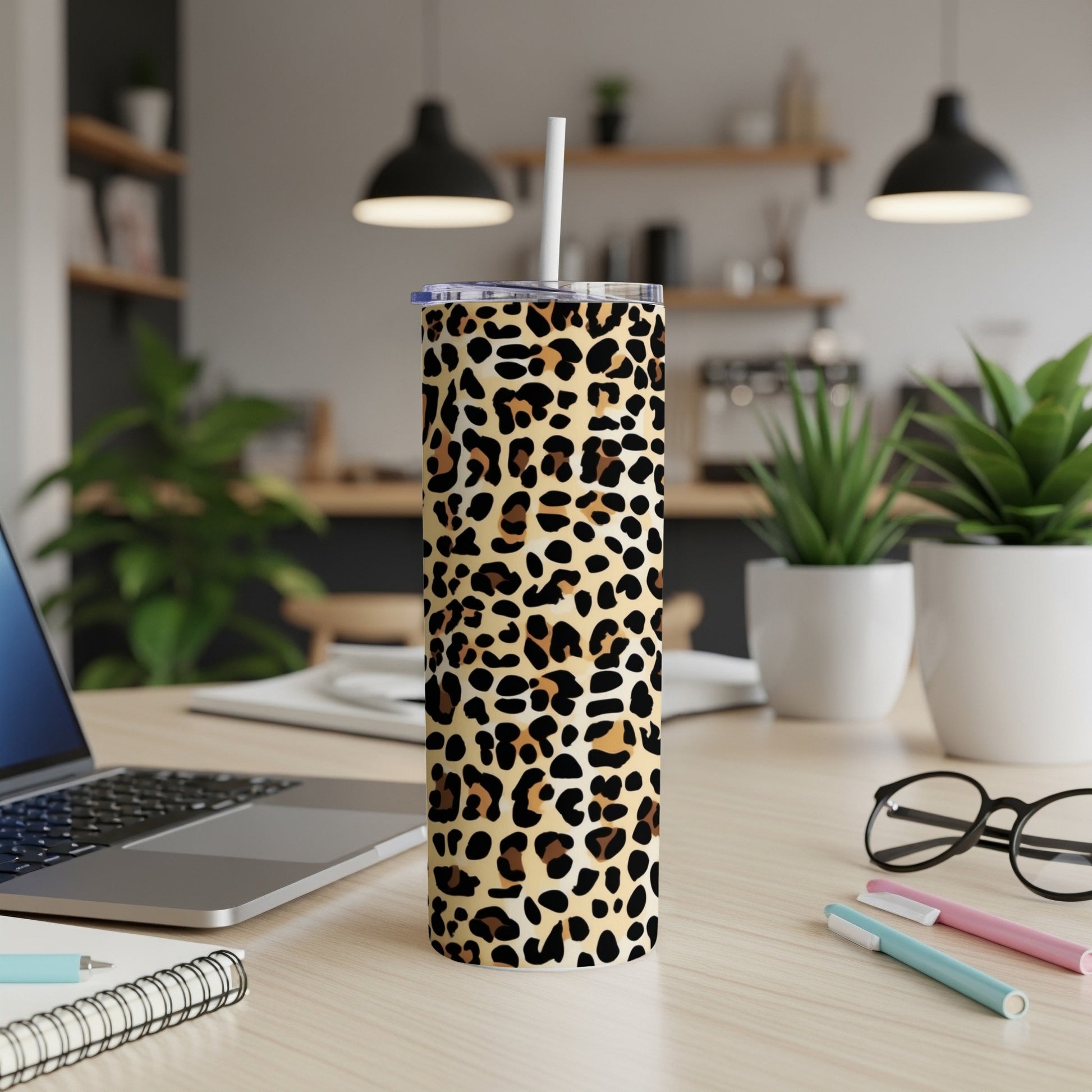 Leopard print tumbler with straw on a desk with a laptop and pens.