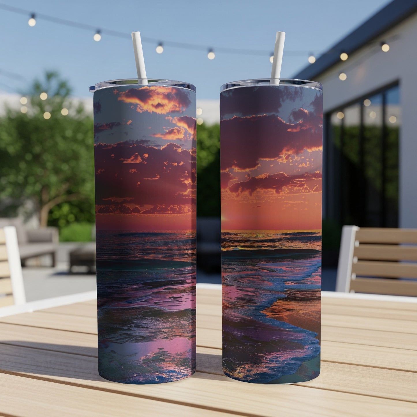 Two tumblers with ocean sunset design on a wooden table outdoors.