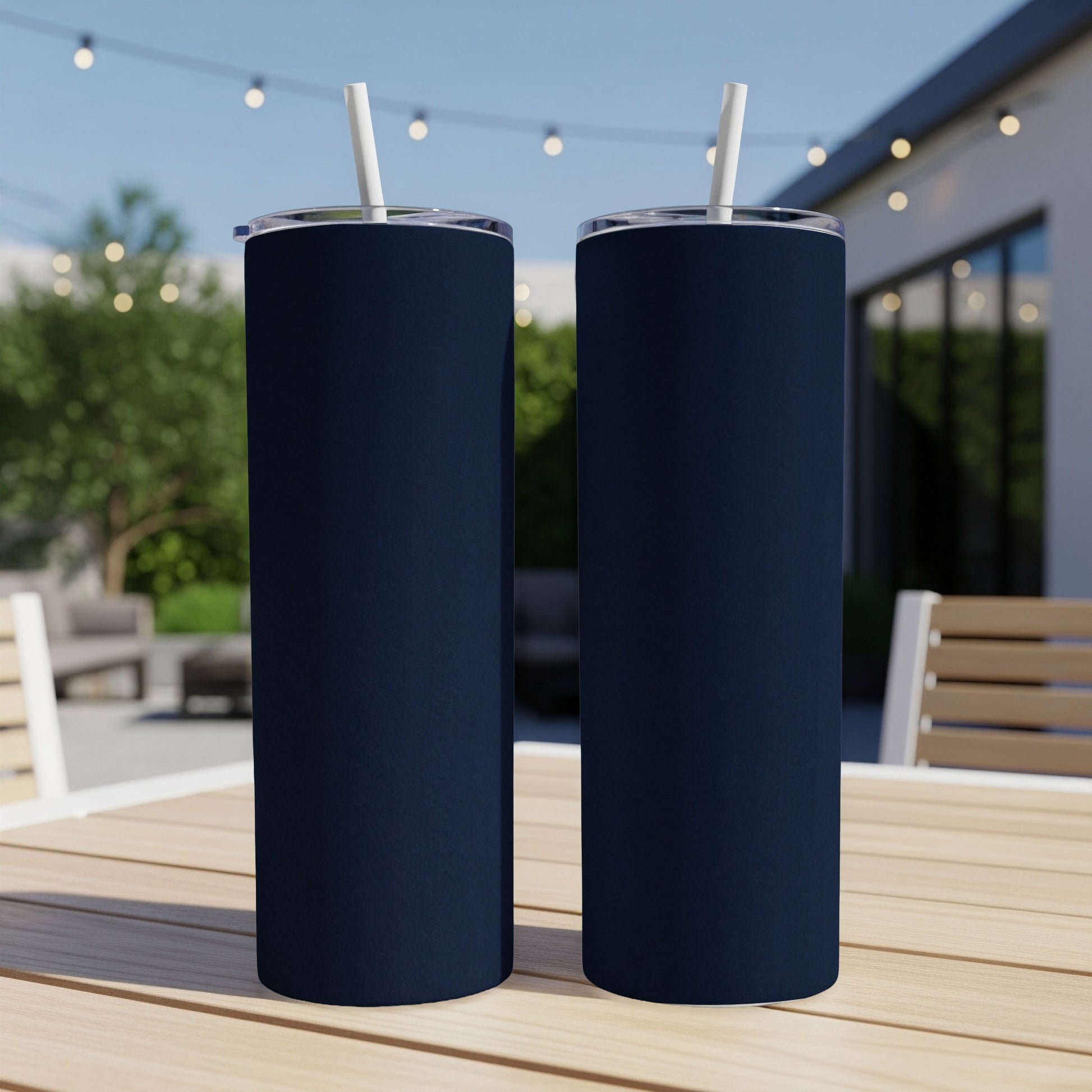 Two navy blue tumblers with white straws on a wooden table.