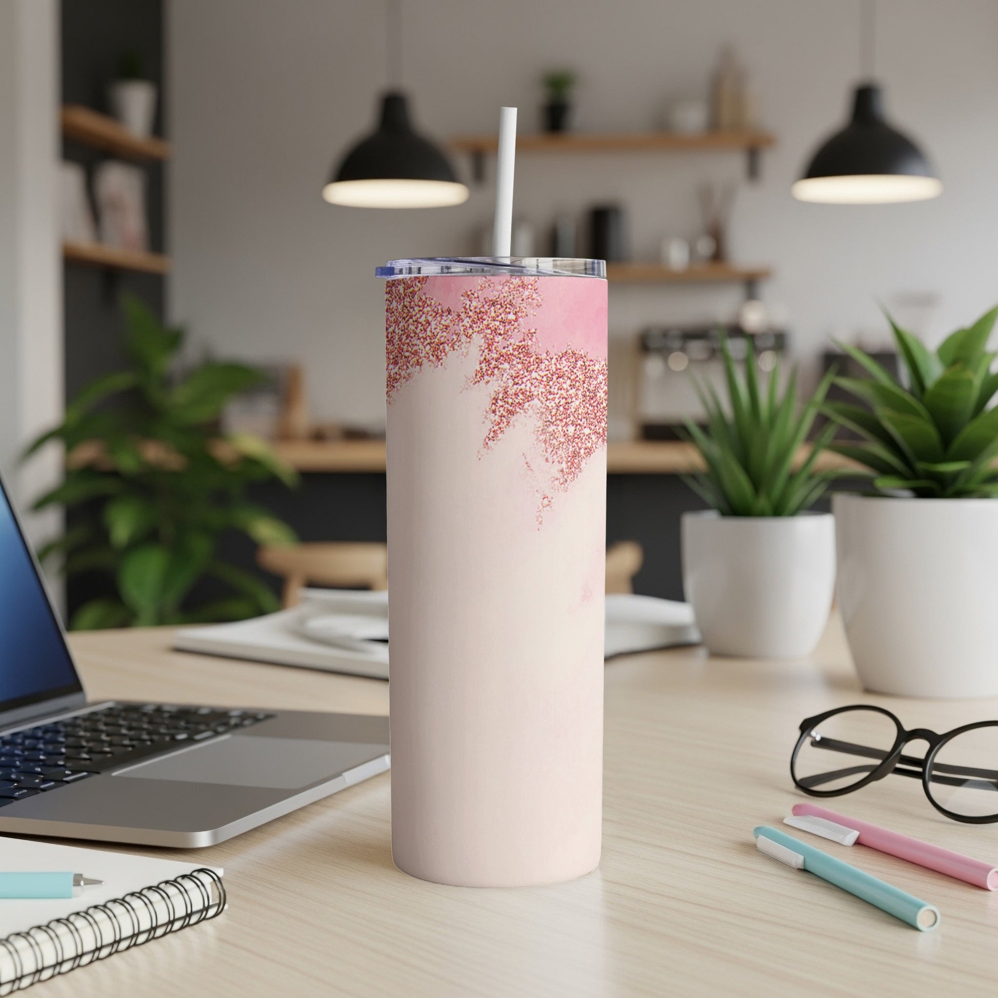 Pink glitter swirl skinny tumbler with straw on desk.