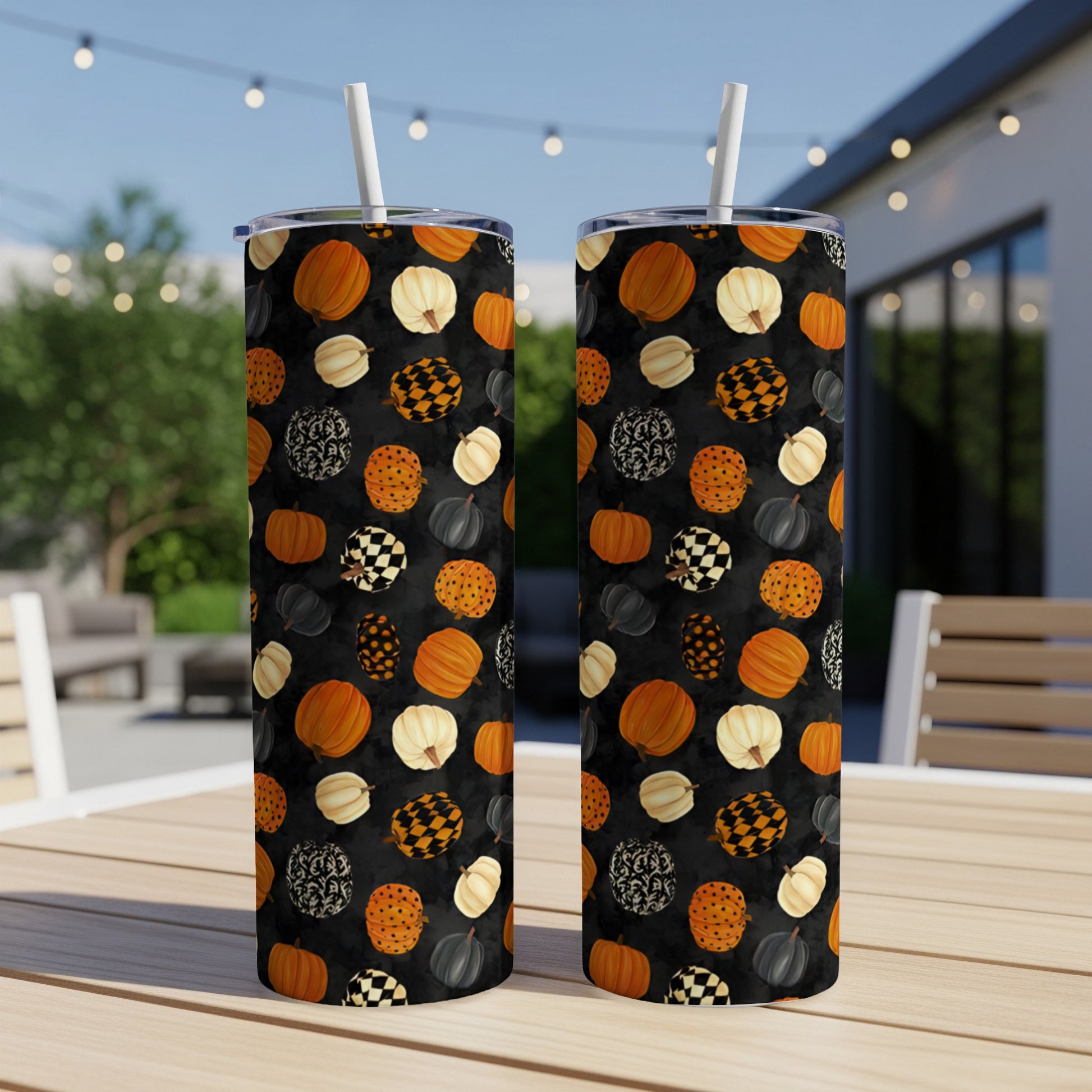 Two tumblers with a black background and a pattern of pumpkins, checkerboard, and floral shapes.