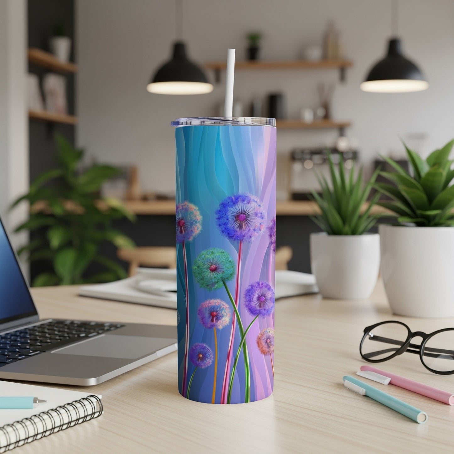 Tall tumbler with colorful dandelion print and straw on desk.