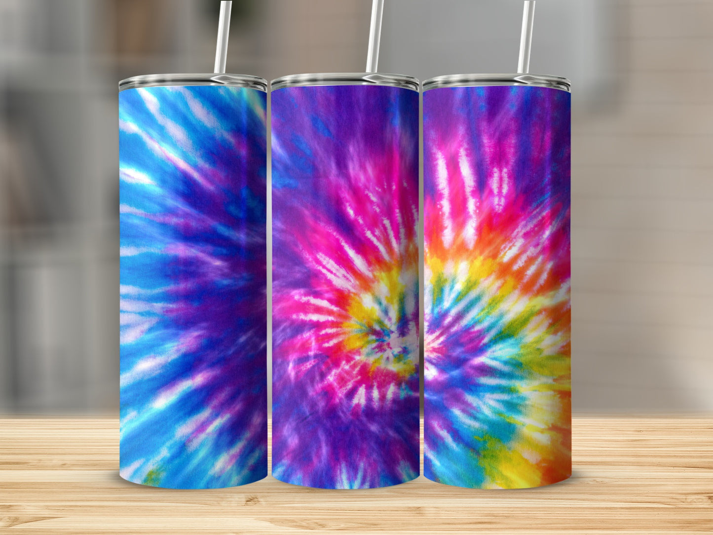 Three tumblers with colorful tie-dye patterns displayed on a wooden surface.