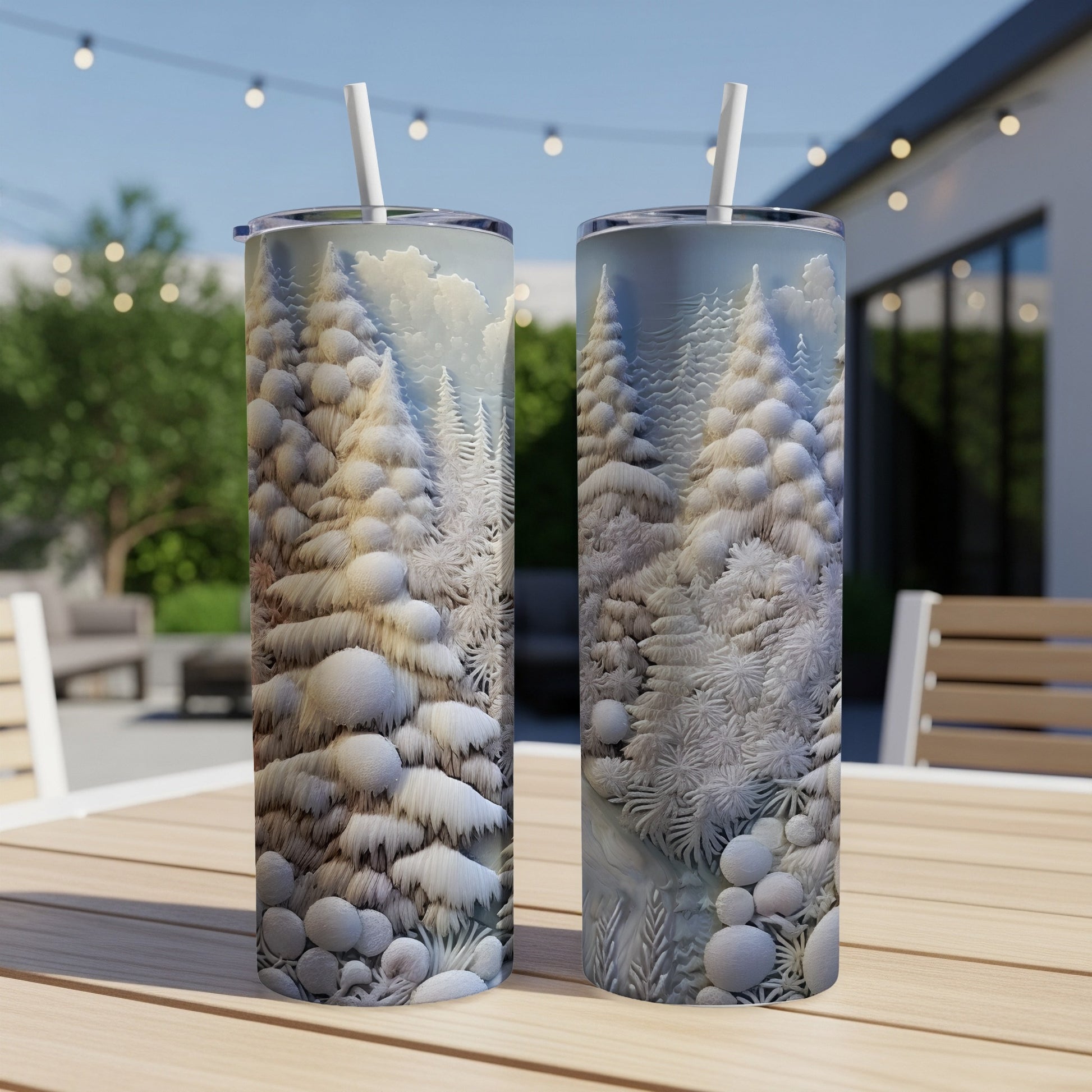 Two snow-covered pine trees on a white tumbler, resting on a wooden table outdoors.