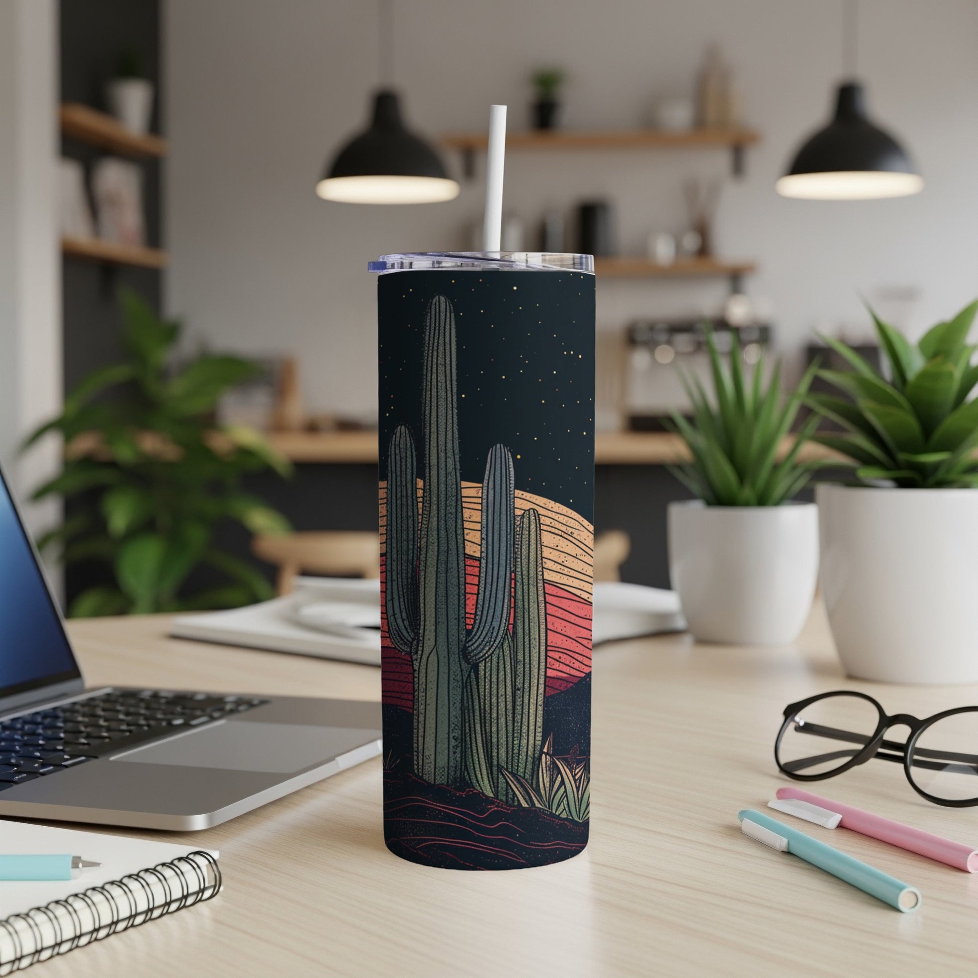 Desert sunset scene on a tall tumbler with a straw, on a desk.