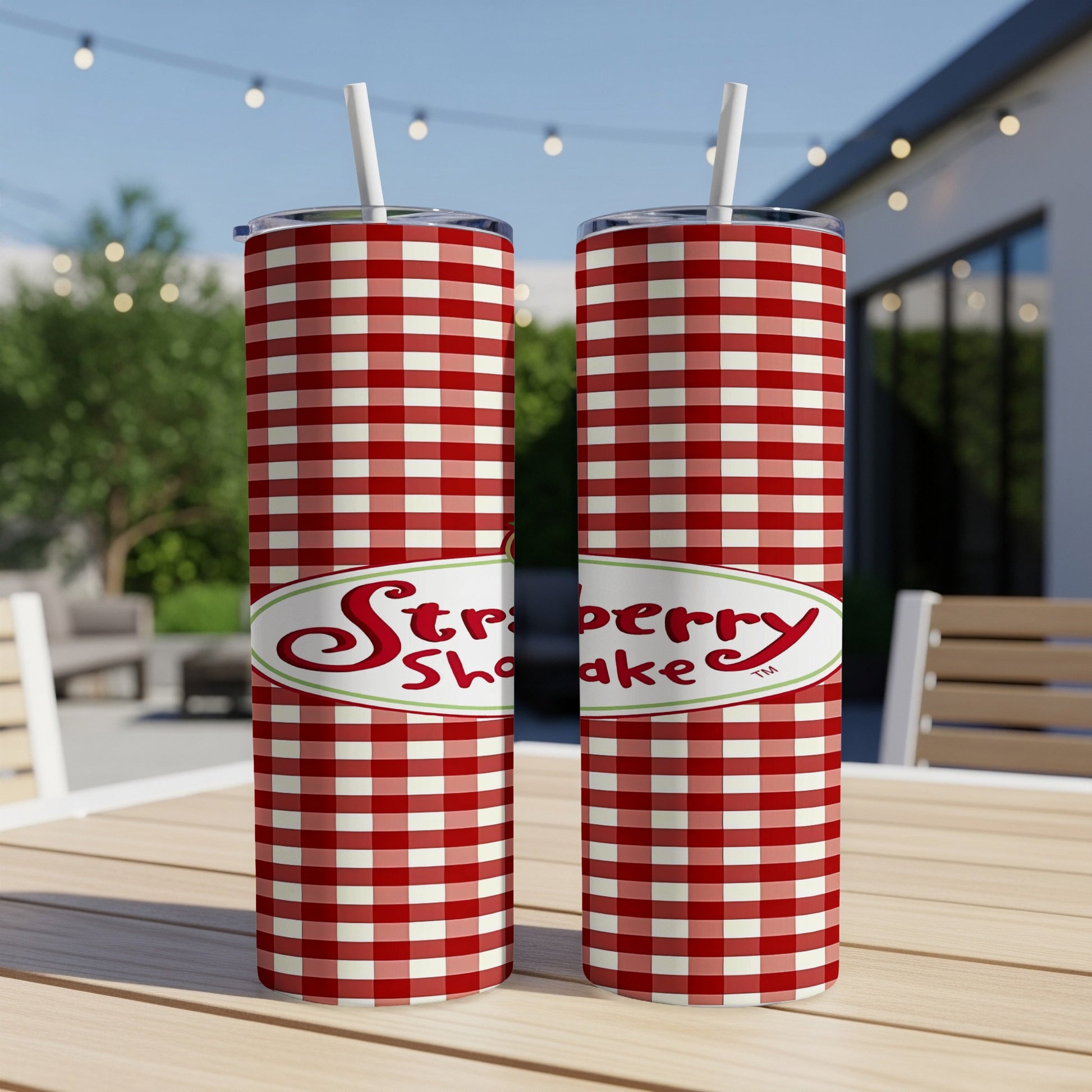 Two red and white checkered tumblers with "Strawberry Shake" label on a table.