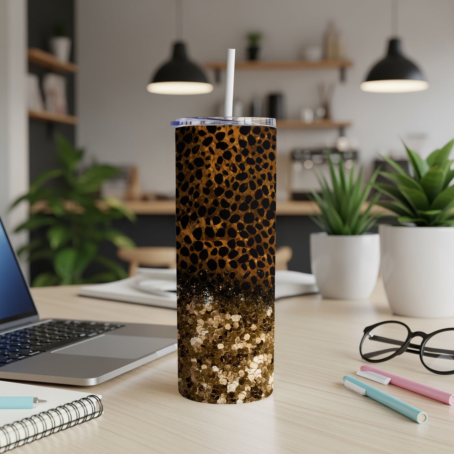 Leopard print glitter tumbler with straw on a desk.