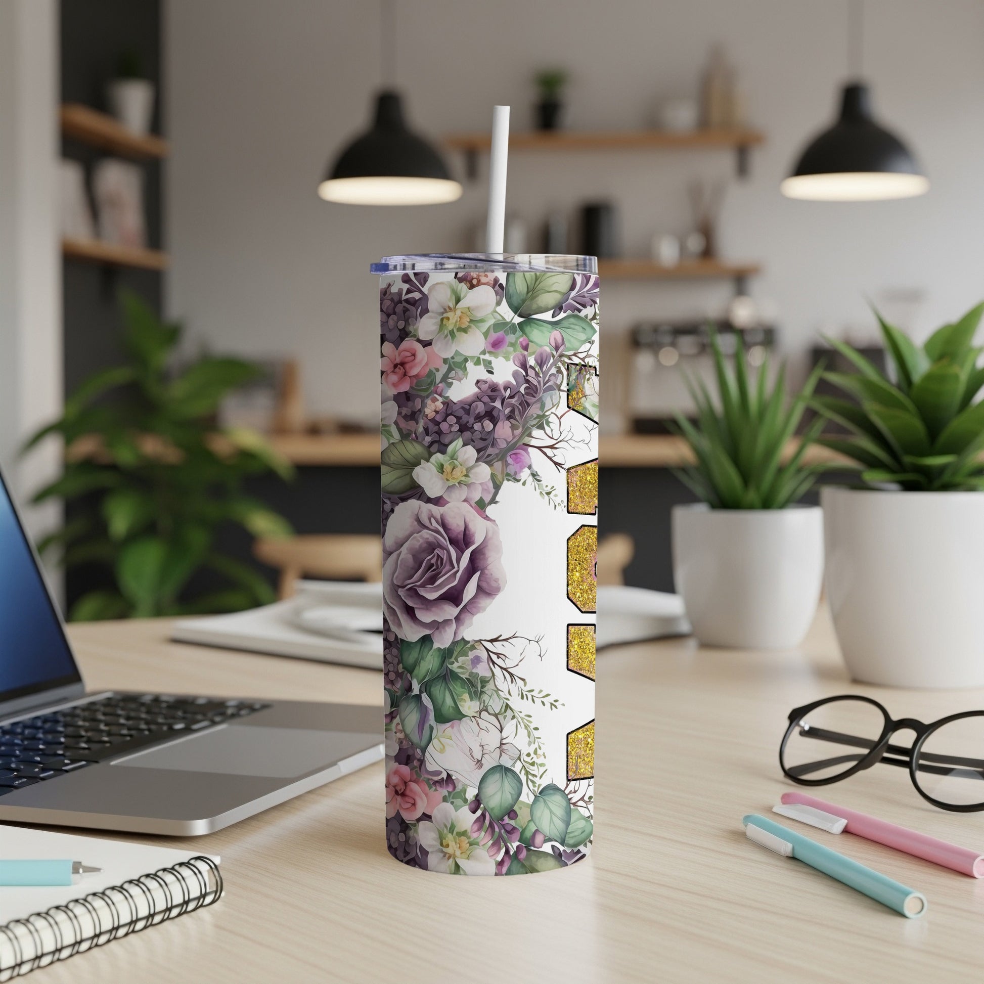 Floral tumbler with straw on a desk next to a laptop.