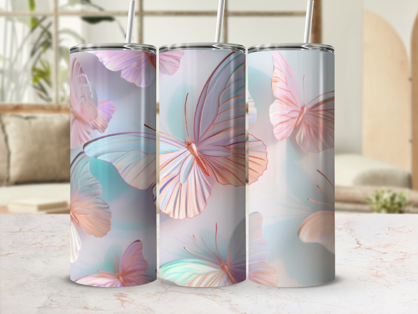 Three tumblers with pastel butterfly designs and straws in a home setting.