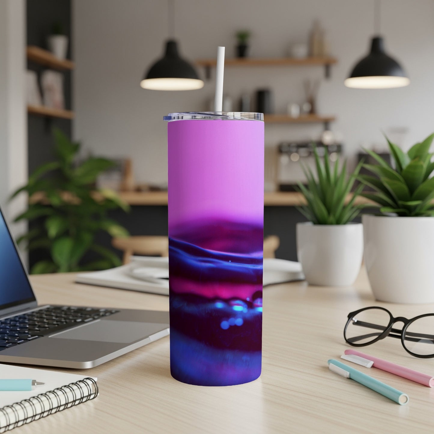 Tall purple and blue abstract pattern tumbler with a straw, on a desk.