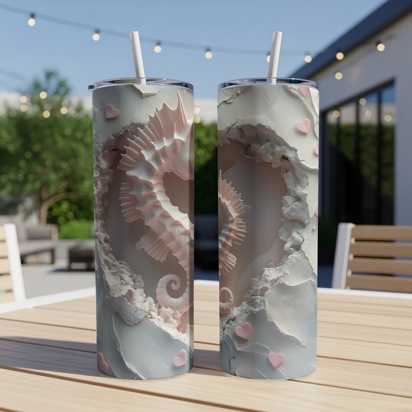 Two pink and white seahorse tumblers with hearts on a table outdoors.