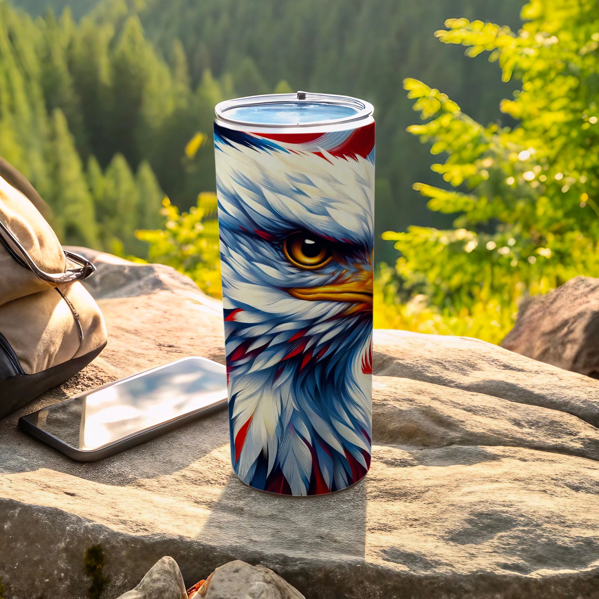 Tumbler with detailed bald eagle design on outdoor rocky surface.