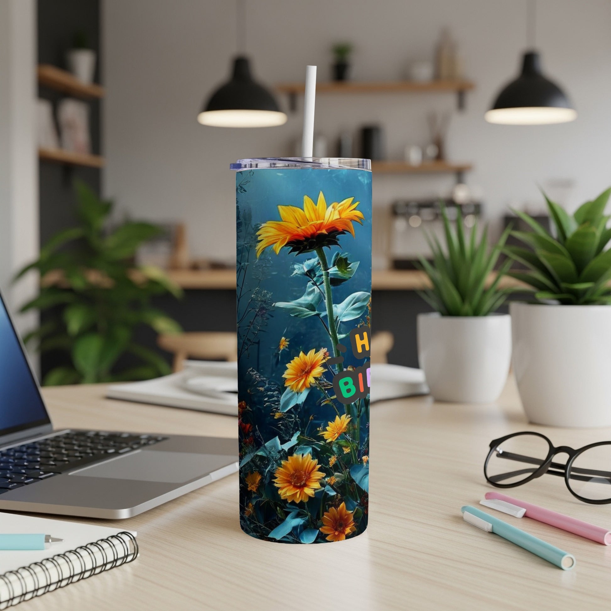 Sunflower design on a tall, skinny tumbler with a straw, sitting on a desk.