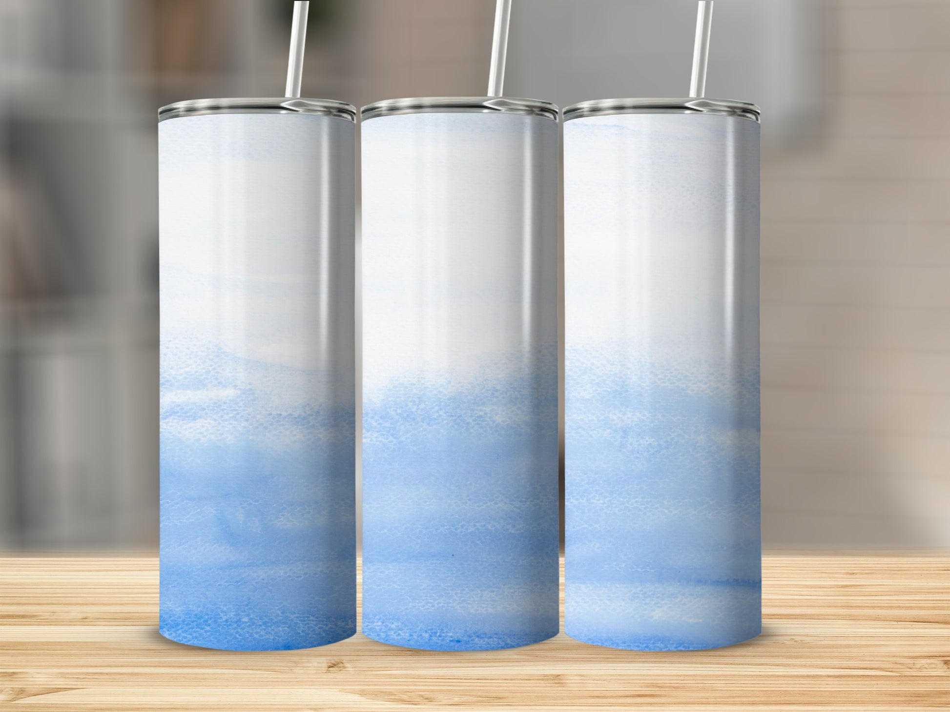 Three white tumblers with blue watercolor accents and straws.