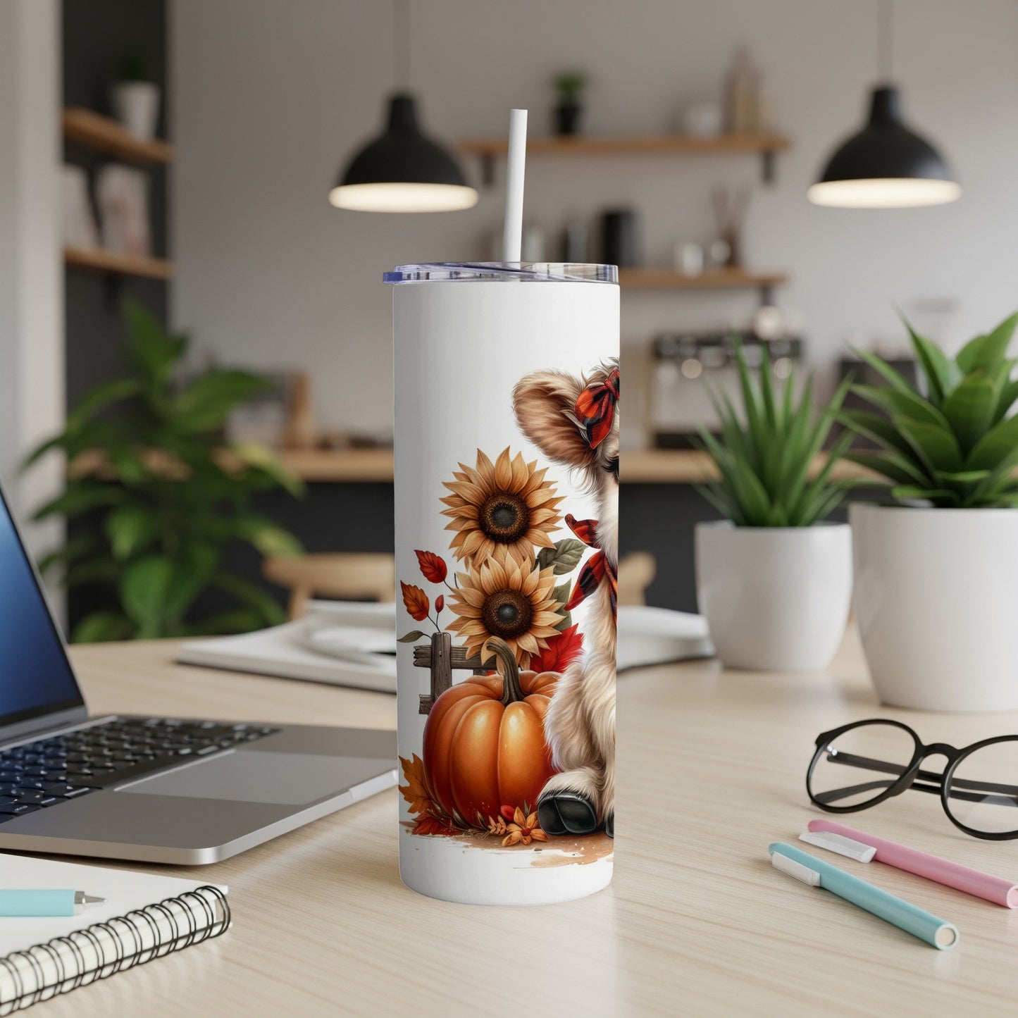 Tumbler with fluffy dog, pumpkins, and sunflowers on a desk.