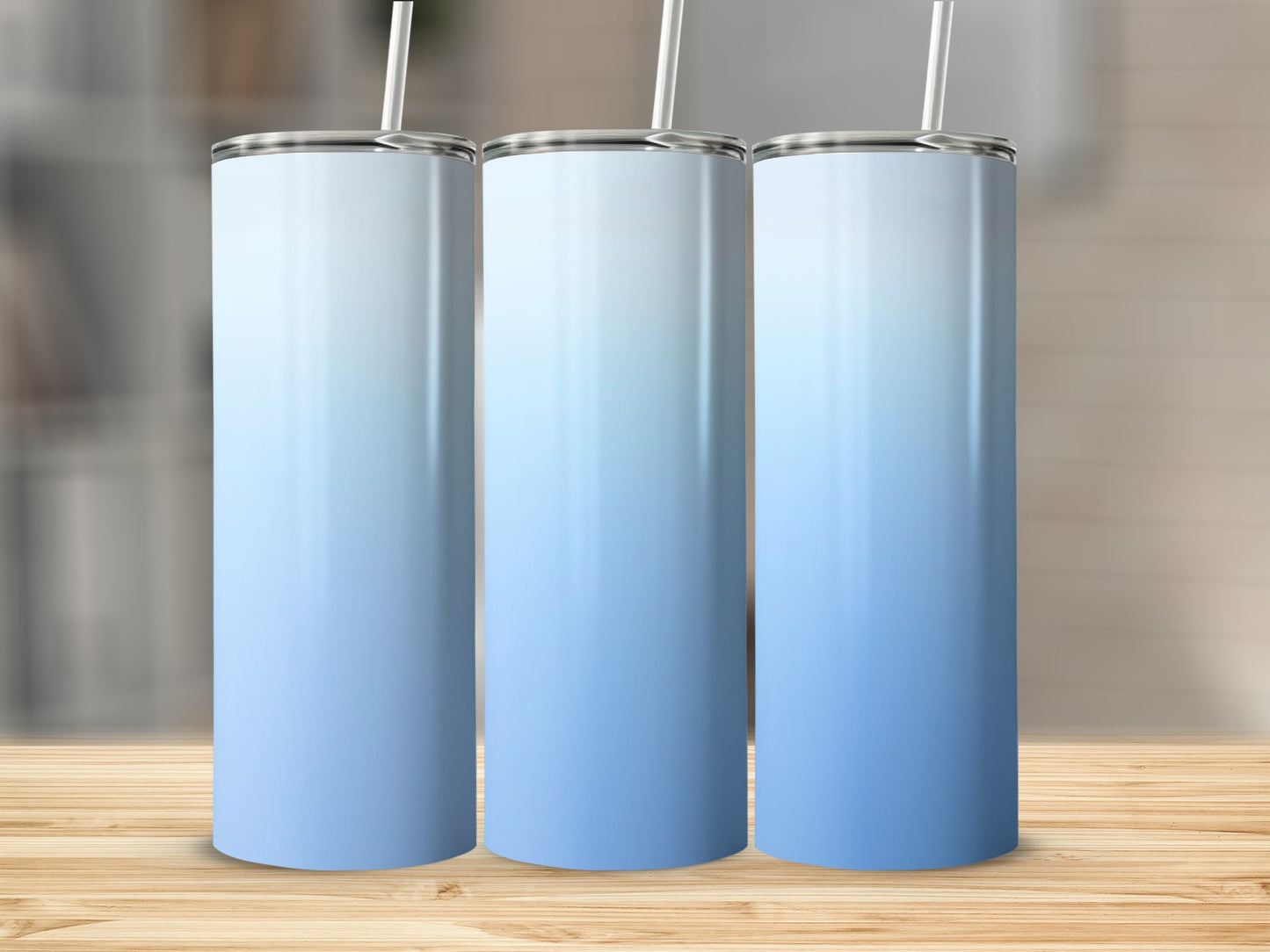 Three blank gradient blue and white tumblers with straws on a wooden surface.
