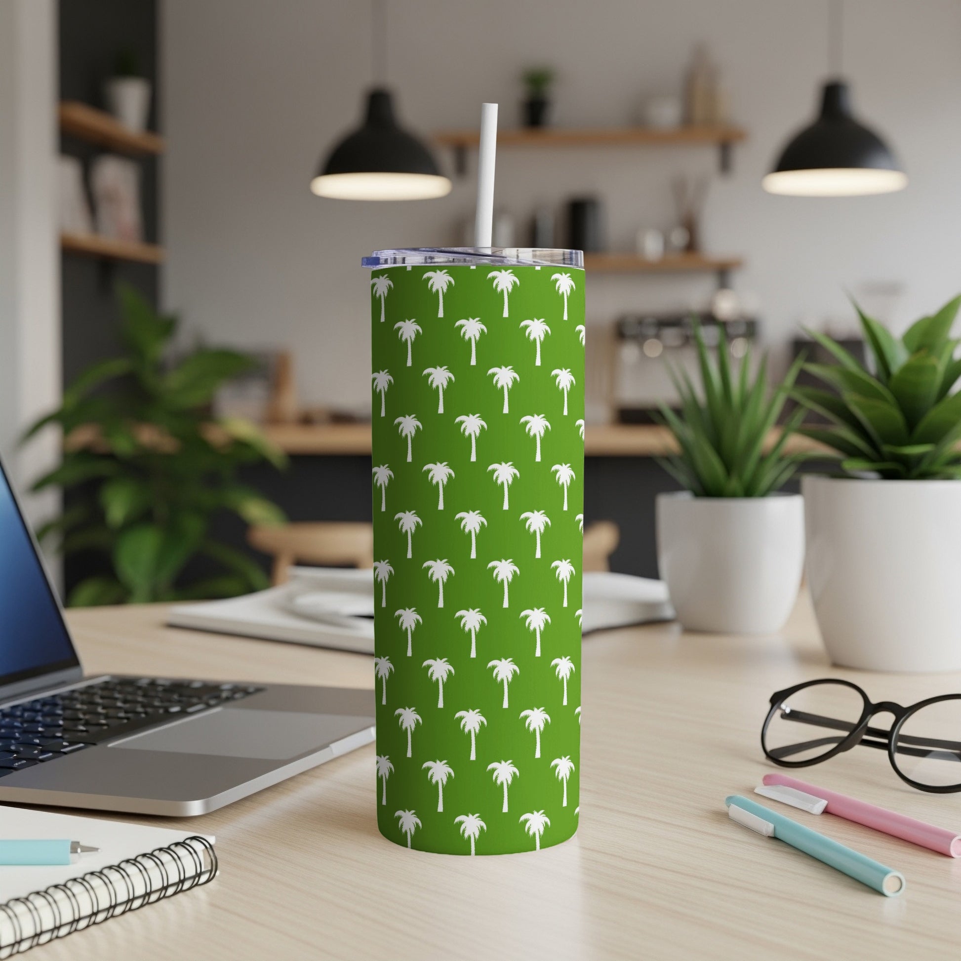Green tumbler with white palm tree pattern and straw.