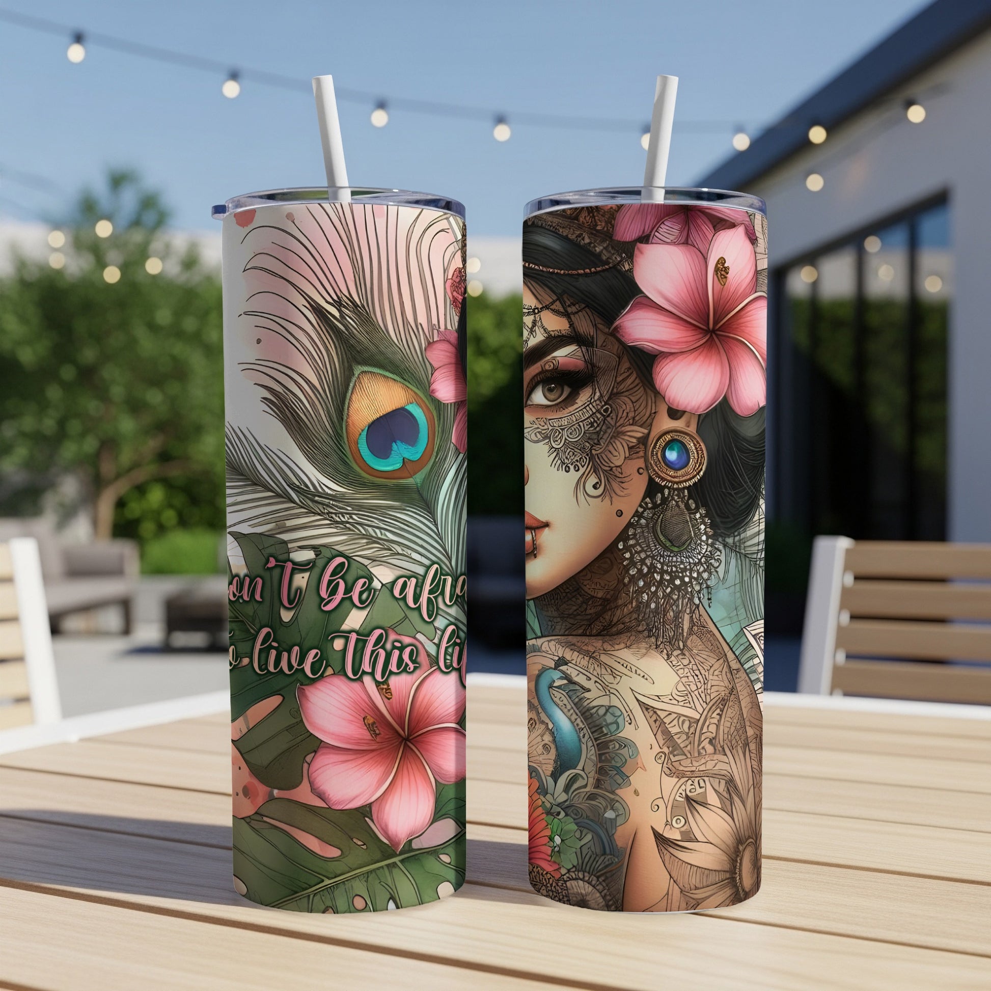 Two tumblers with tattooed woman and floral designs on an outdoor table.