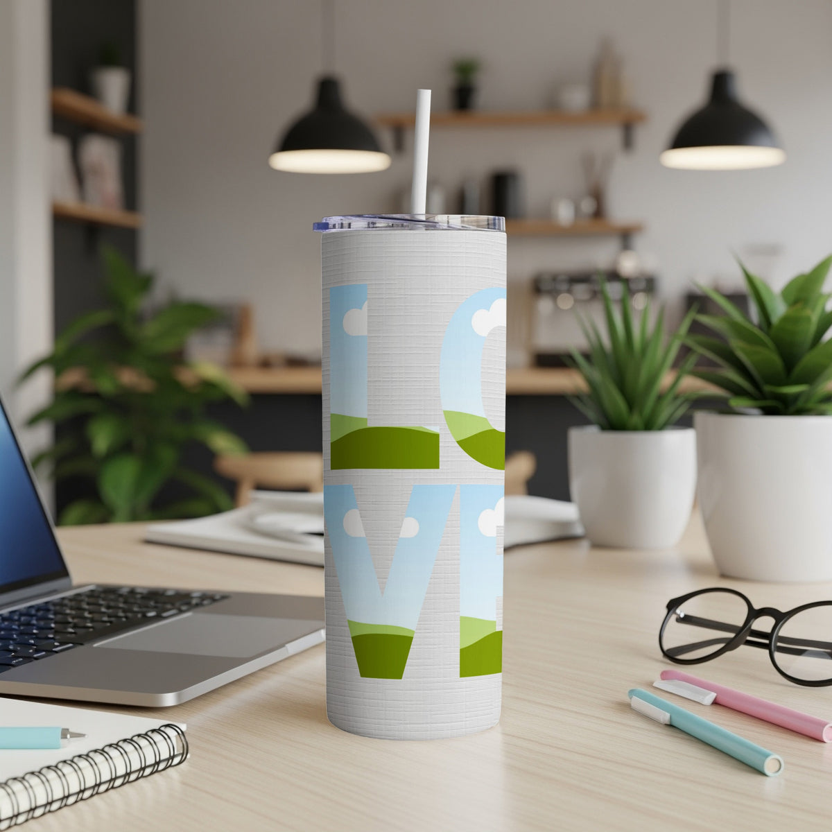 White tumbler with "LOVE" text filled with sky and rolling hills.