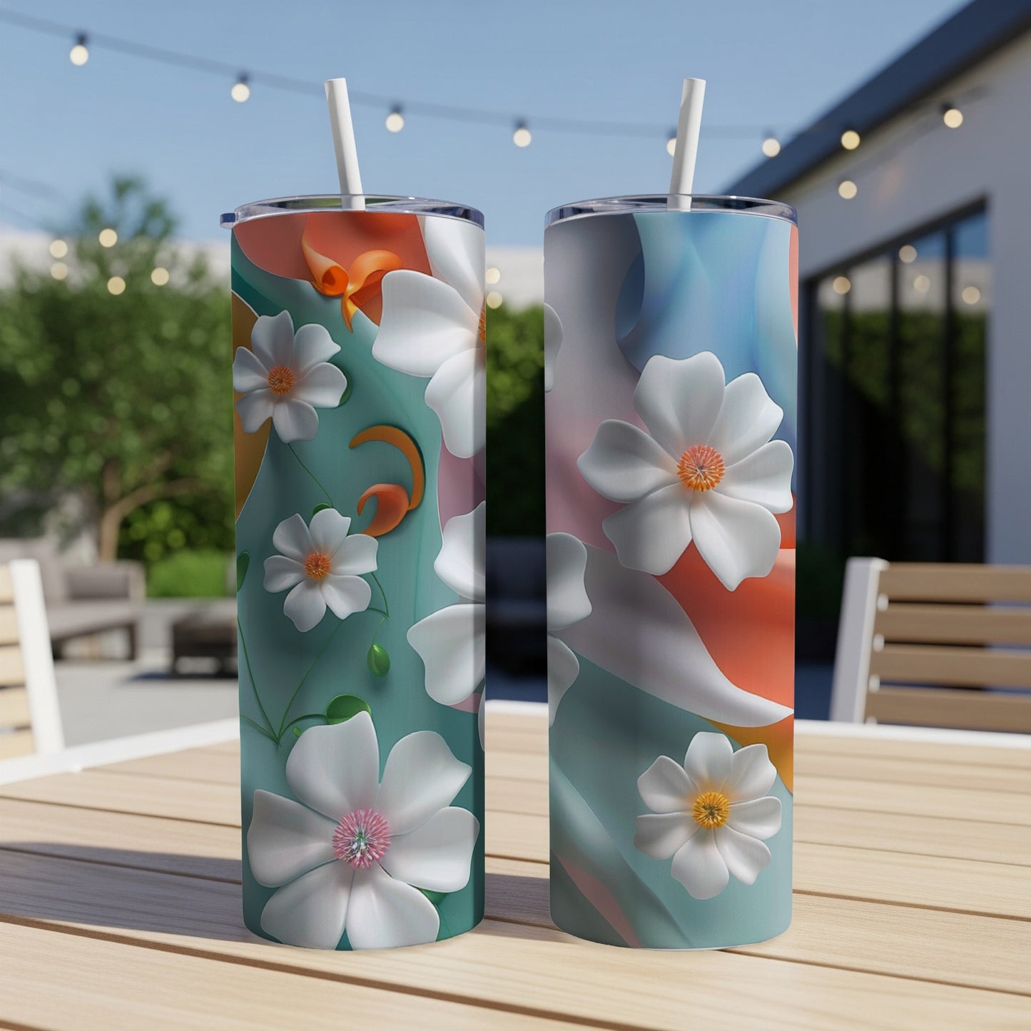 Two tall tumblers with abstract floral patterns and straws, on a wooden table.