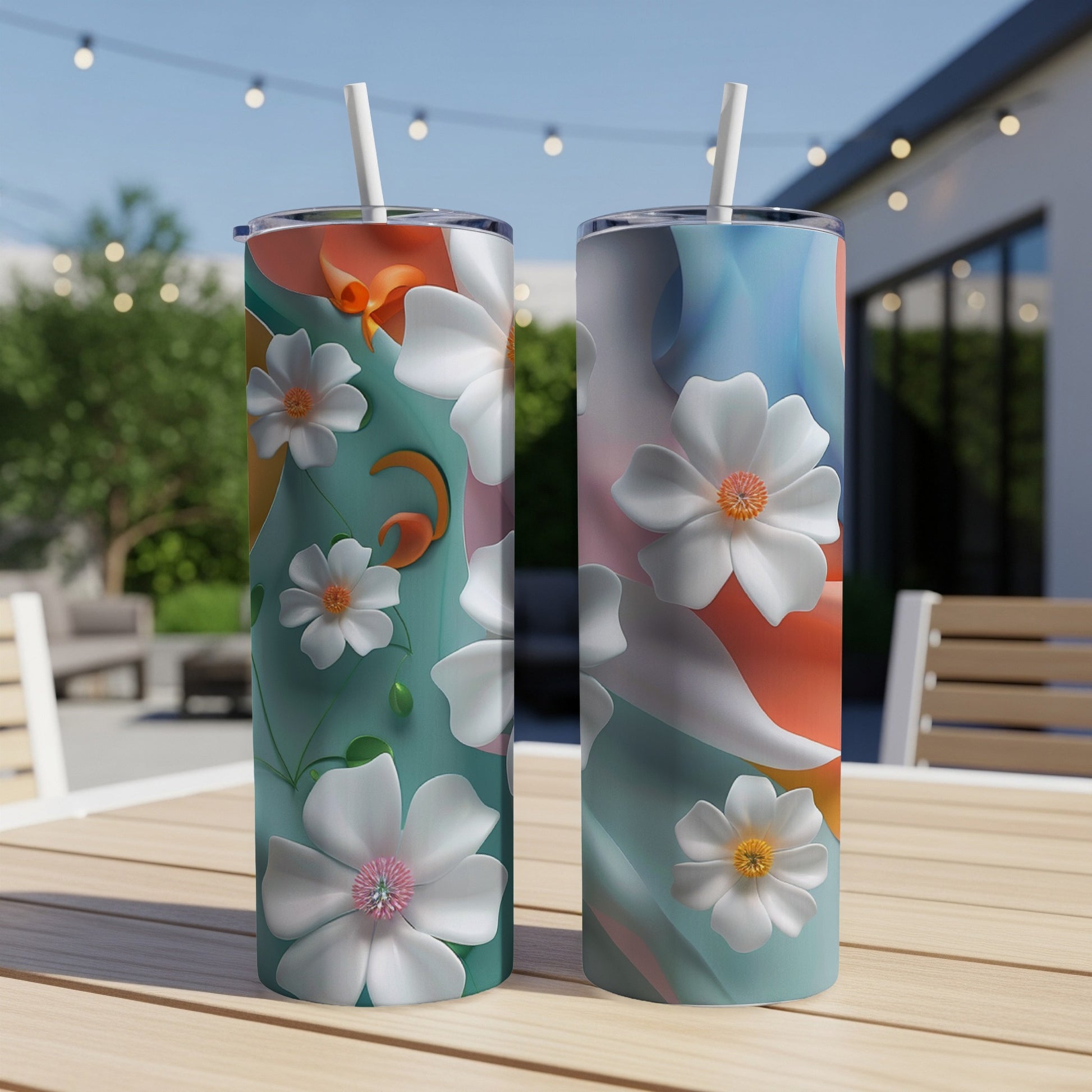 Two tall tumblers with abstract floral patterns and straws, on a wooden table.