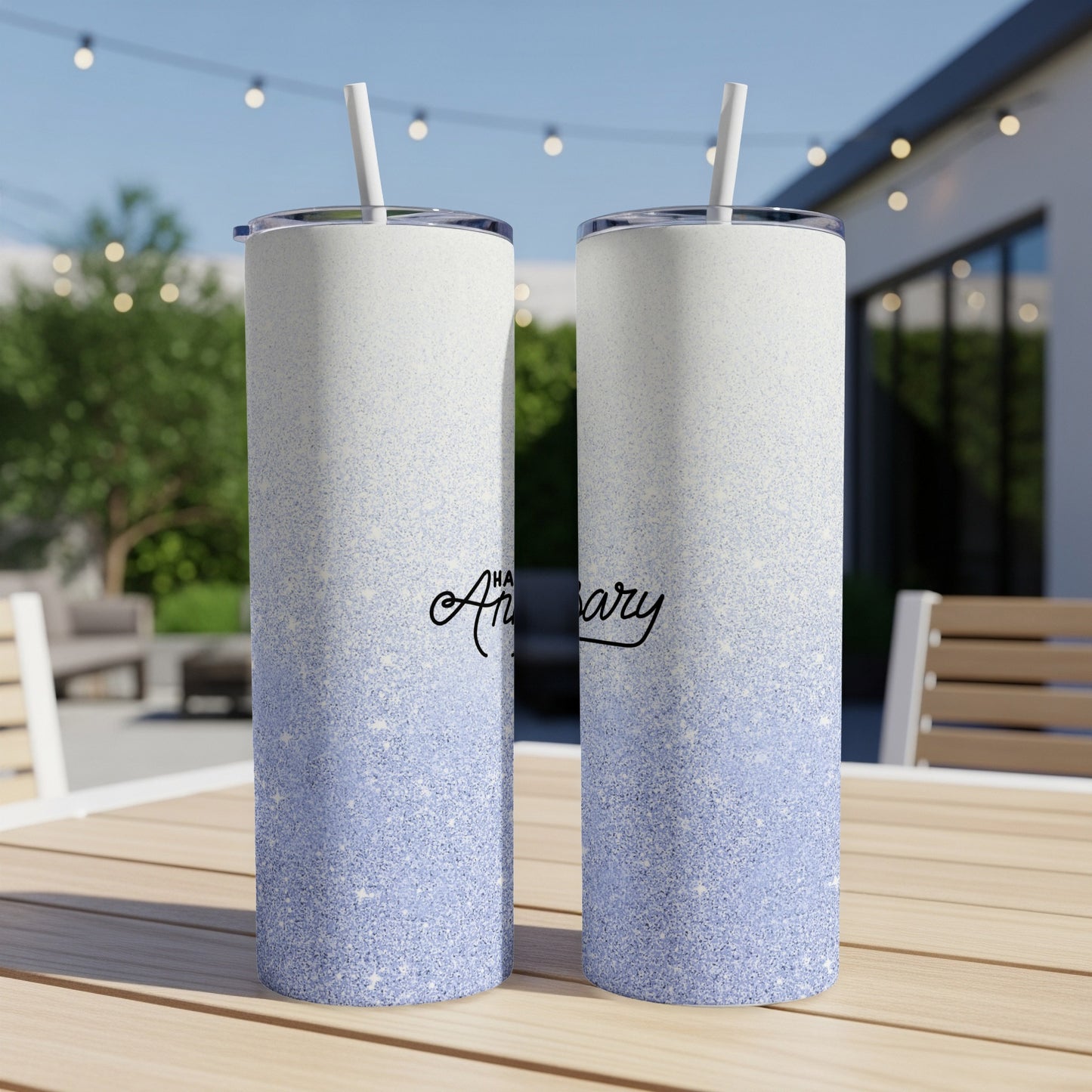Two glittery tumblers with "Anniversary" text on an outdoor table.