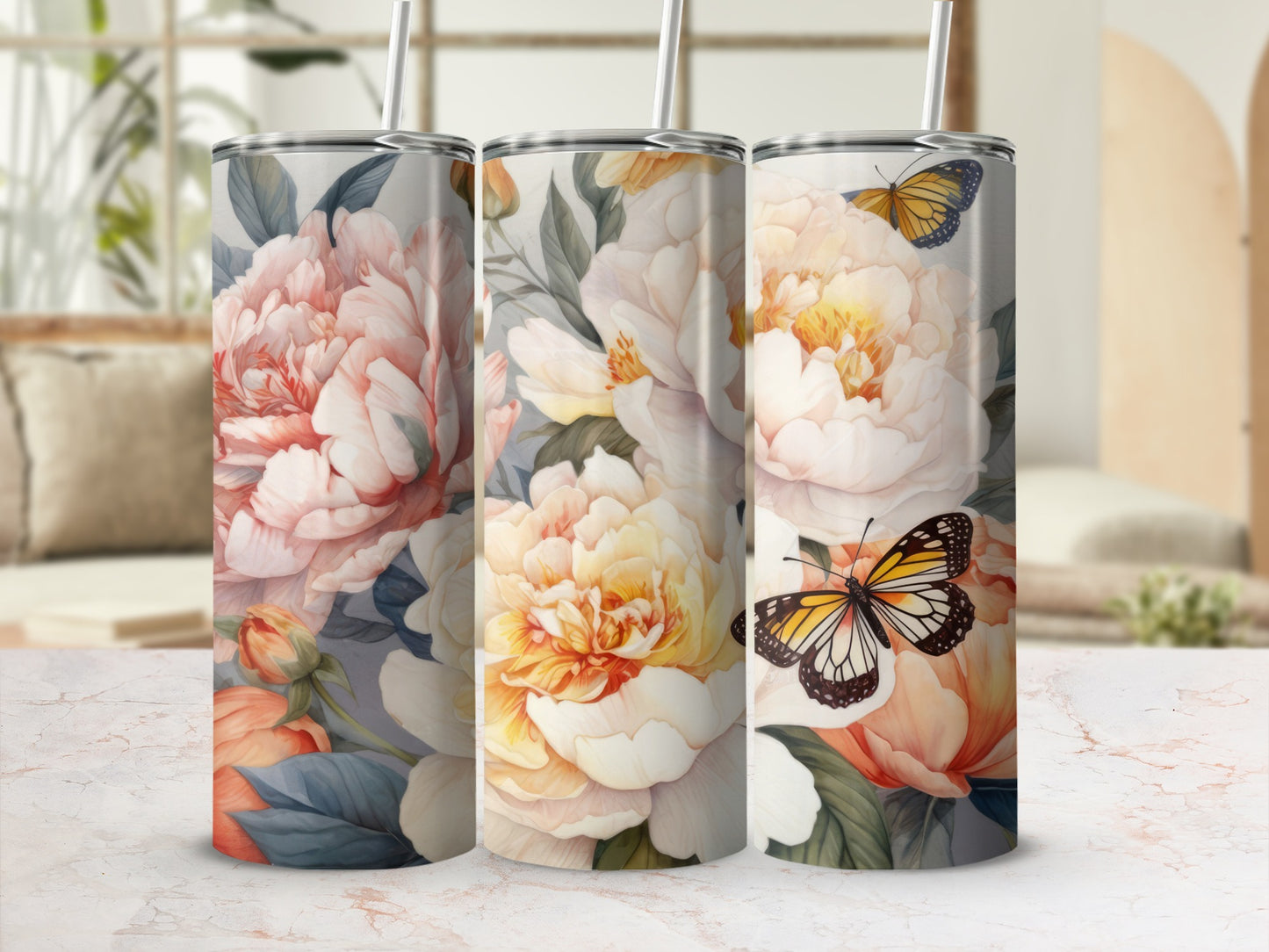 Three tumblers with a floral and butterfly design against a blurred background.