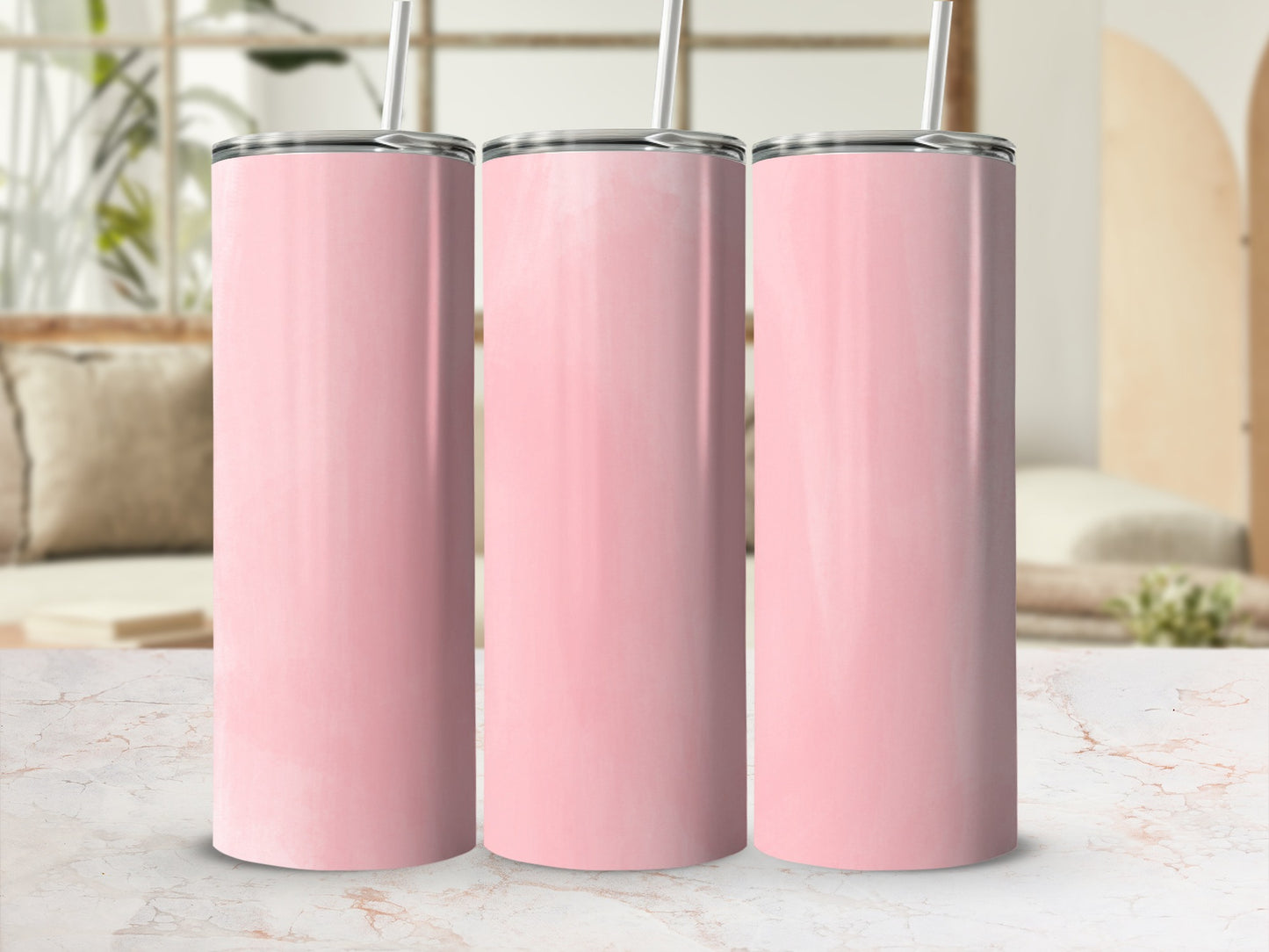 Three pink tumblers with straws stand on a marble surface in a bright room.
