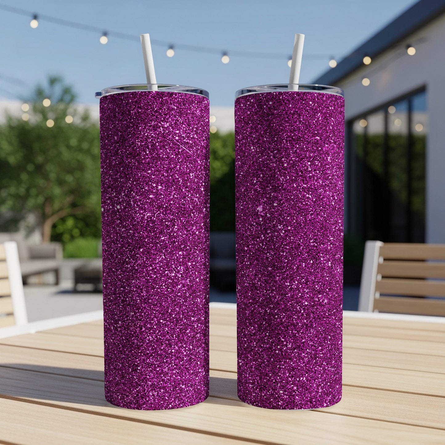 Two glittery purple tumblers with white straws sit on a wooden table outdoors.