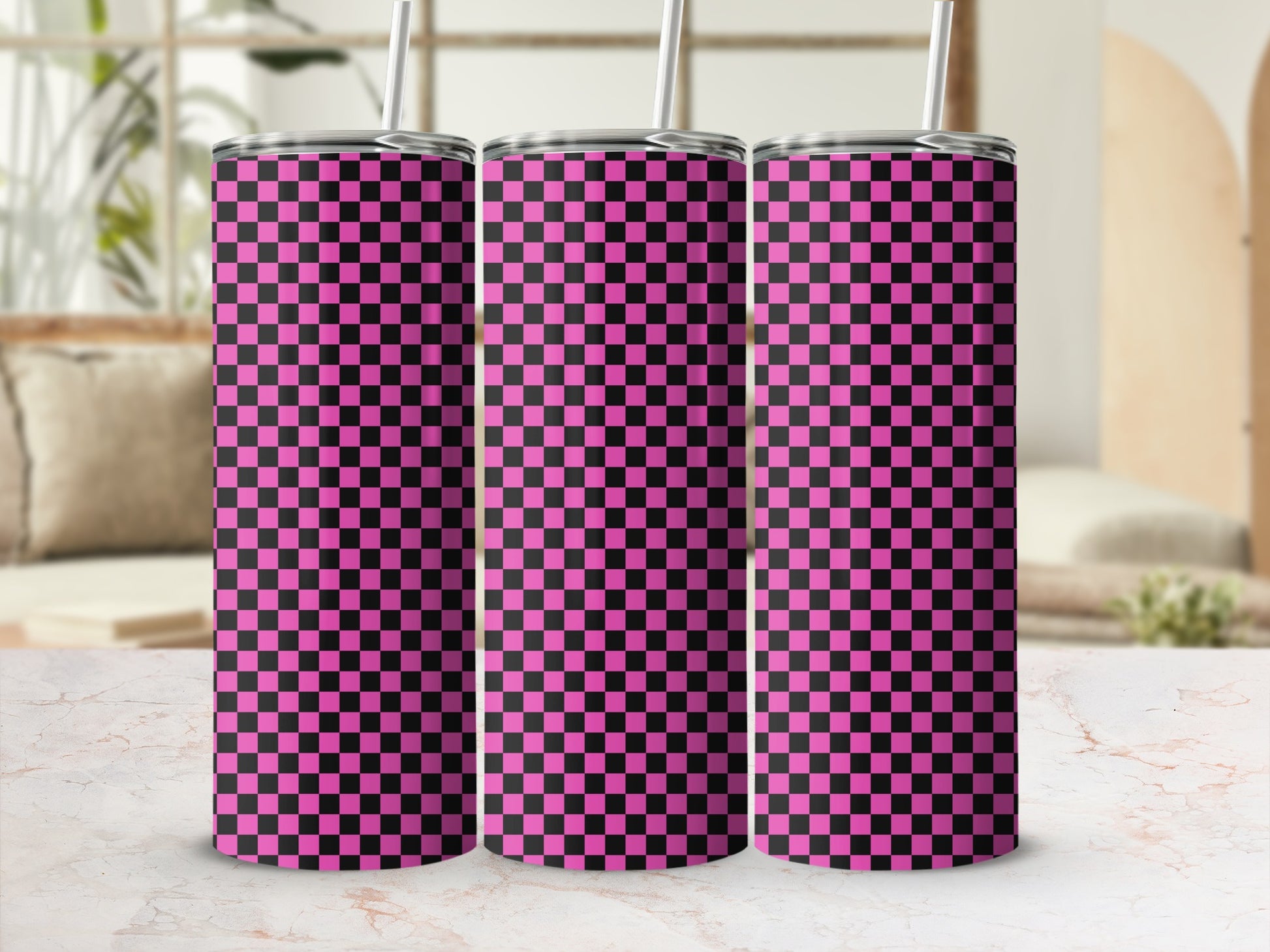 Three pink and black checkered tumblers with straws on a marble surface.