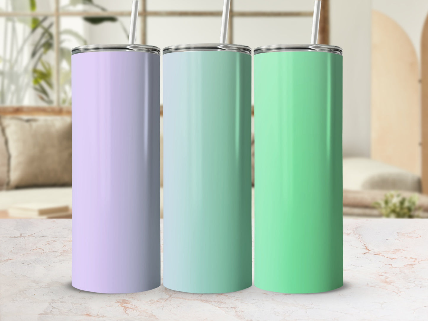 Three pastel colored tumblers with straws on a marble surface.