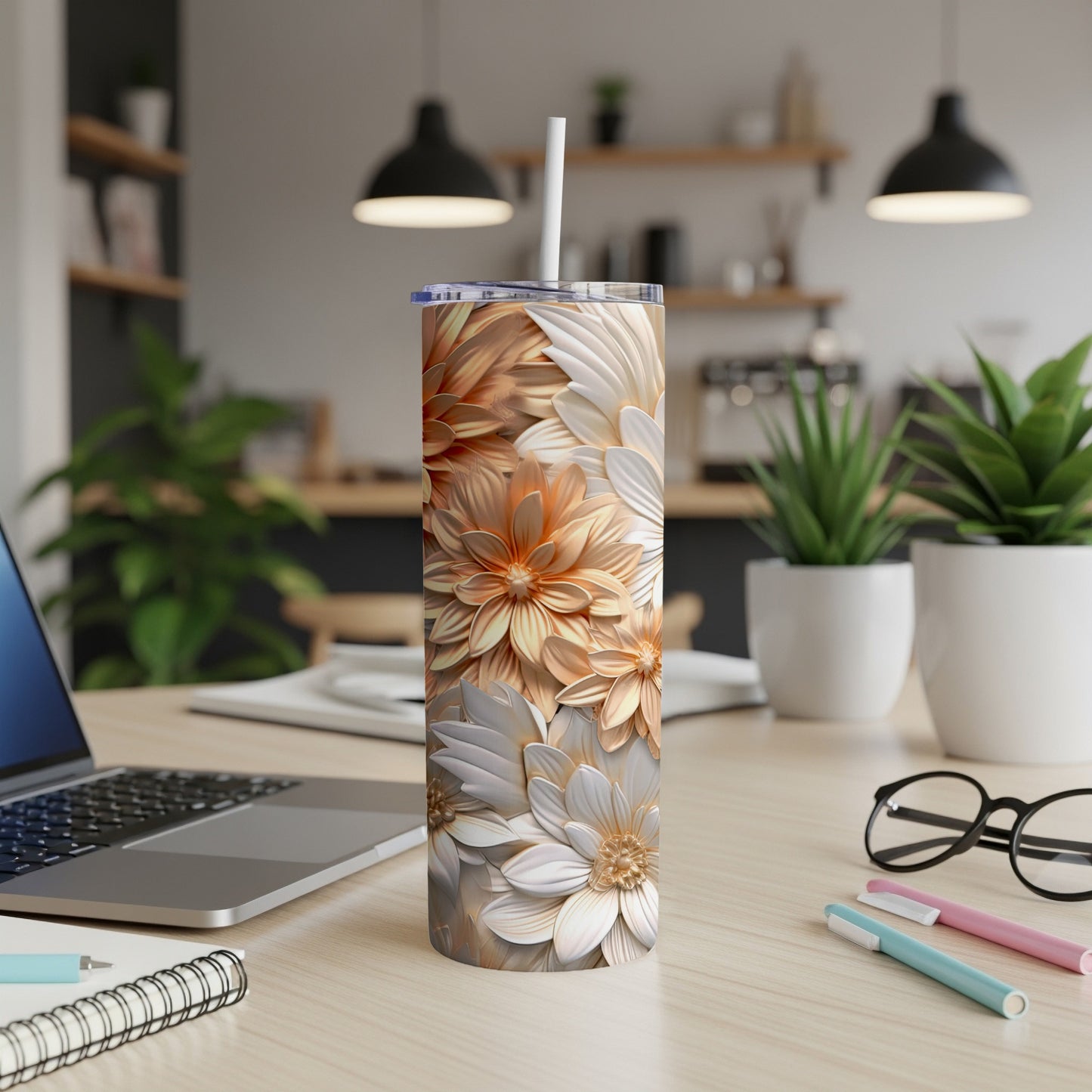 Floral pattern skinny tumbler with straw on a desk.
