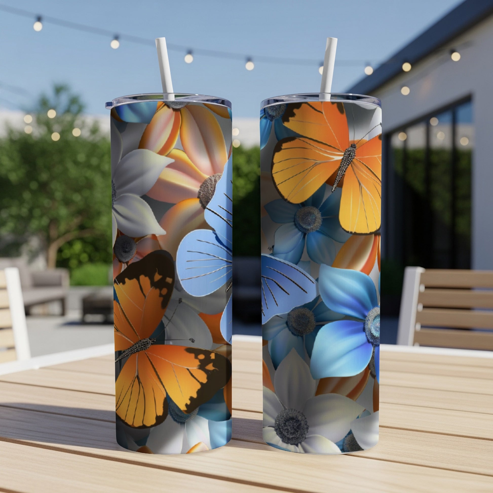 Two tumblers with floral and butterfly designs on a wooden table outdoors.