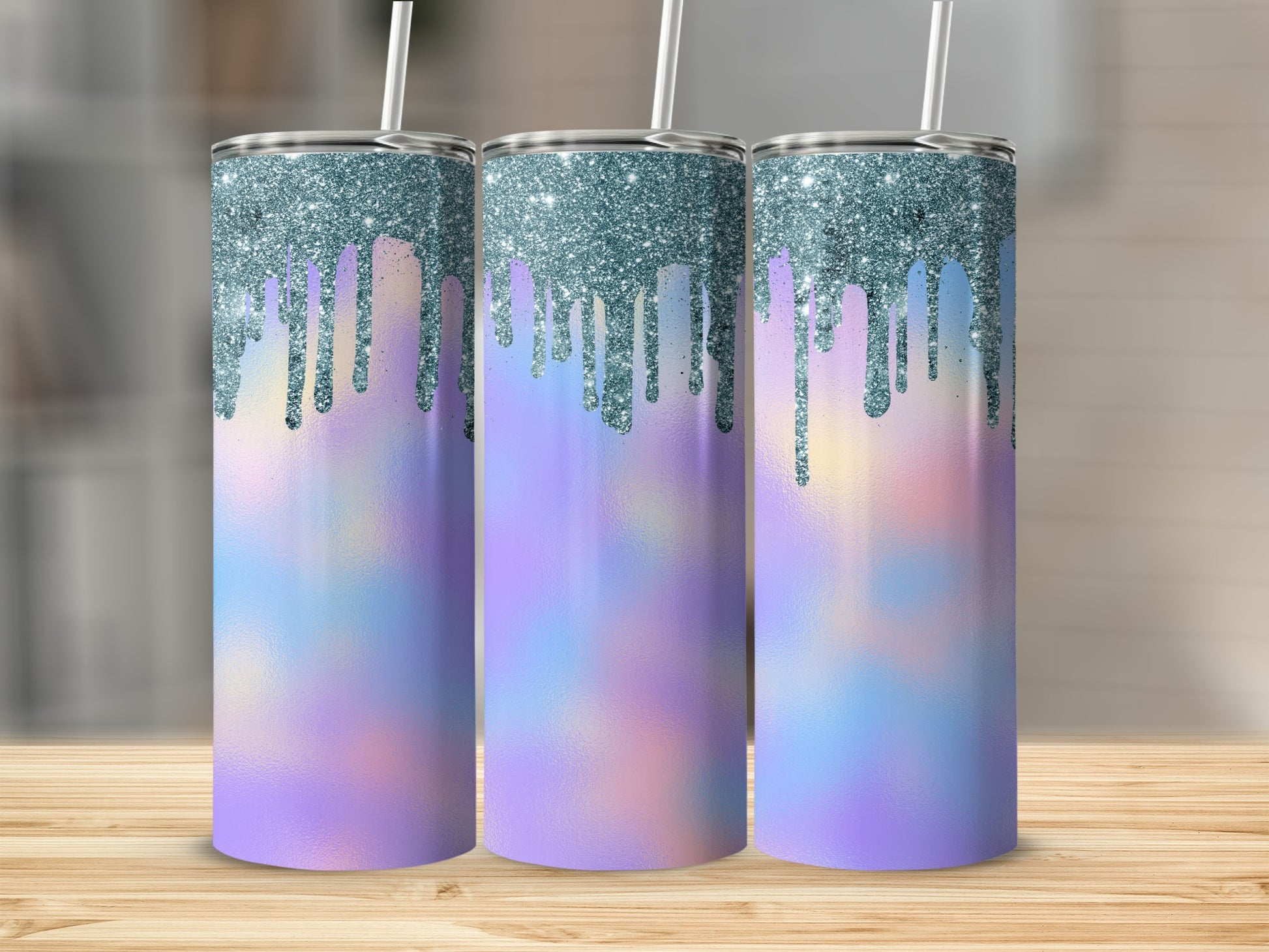 Three iridescent tumblers with blue glitter drip design stand on a wooden surface.