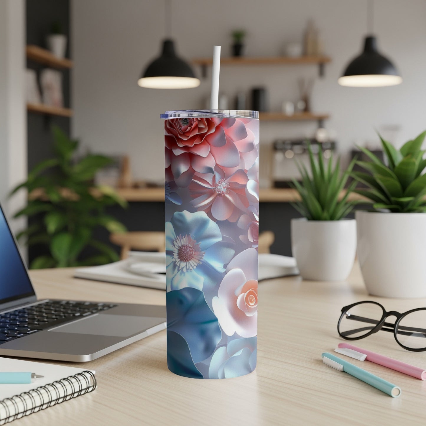 Floral tumbler with straw on a desk next to a laptop.