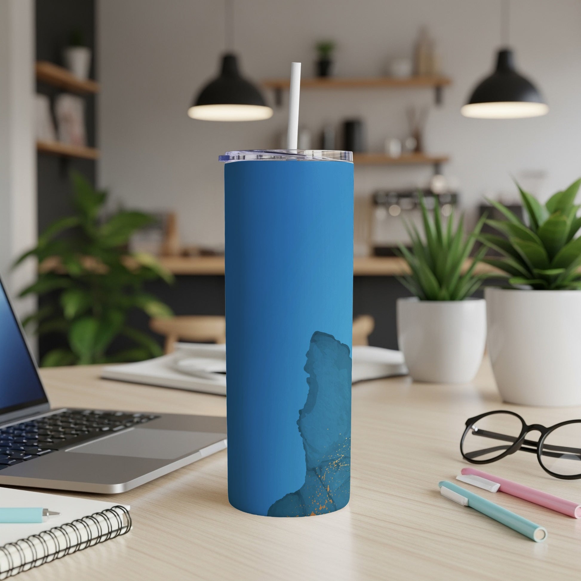 Blue tumbler with abstract gold and white design on desk.
