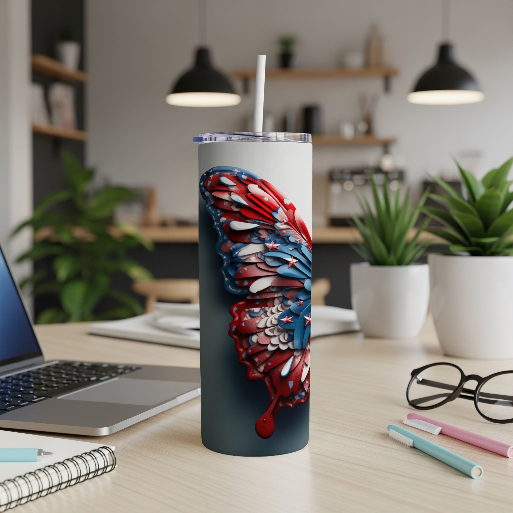 Tall tumbler with a butterfly wing design, on a desk.