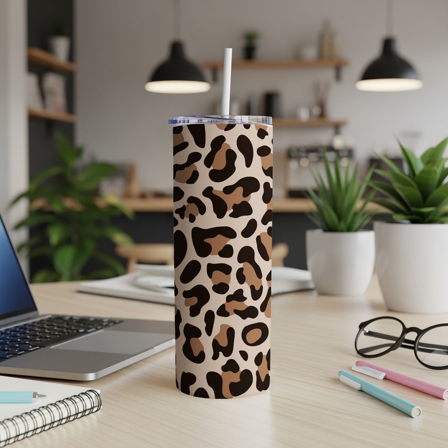 Tumbler with leopard print pattern and straw on a wooden desk.