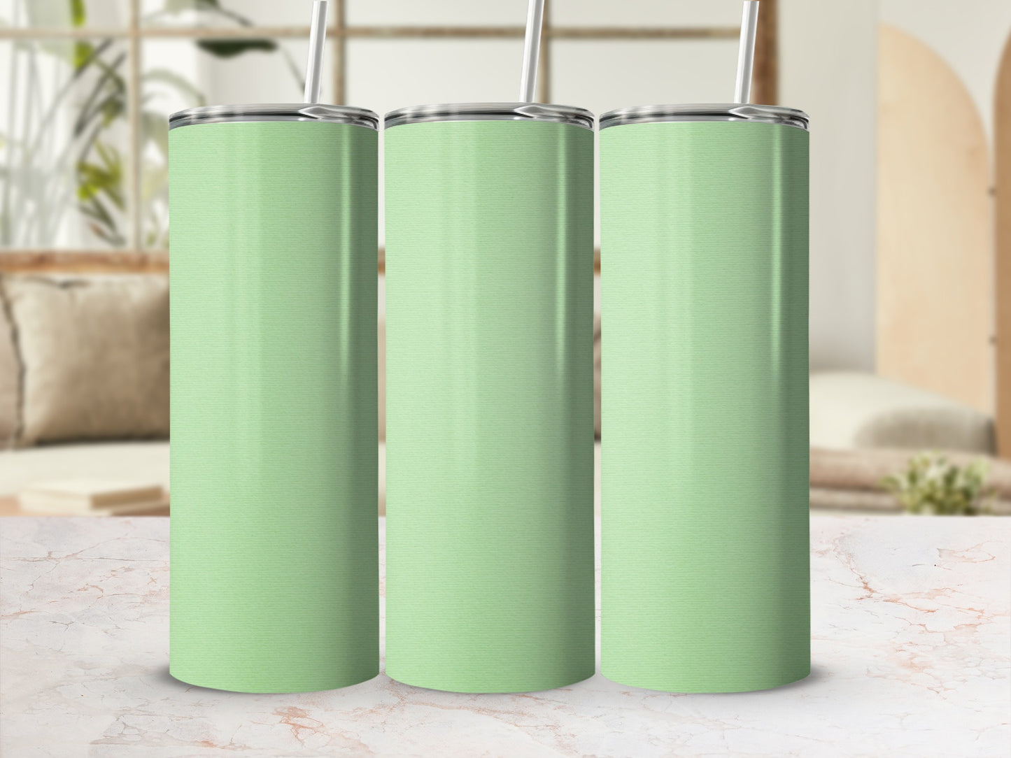Three light green tumblers with straws sit in a row.