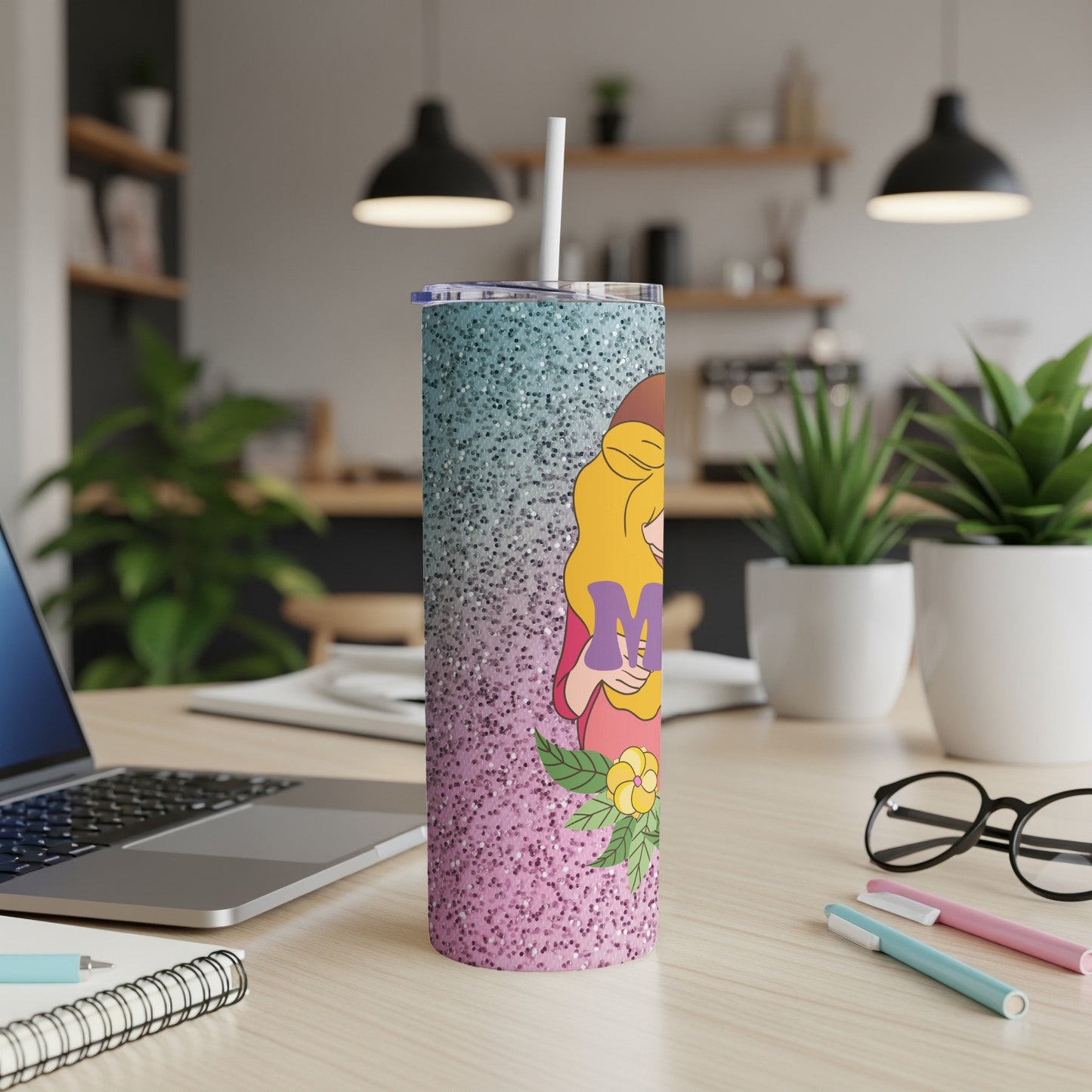 Glitter tumbler with "Mom" lettering and floral accents on a desk.