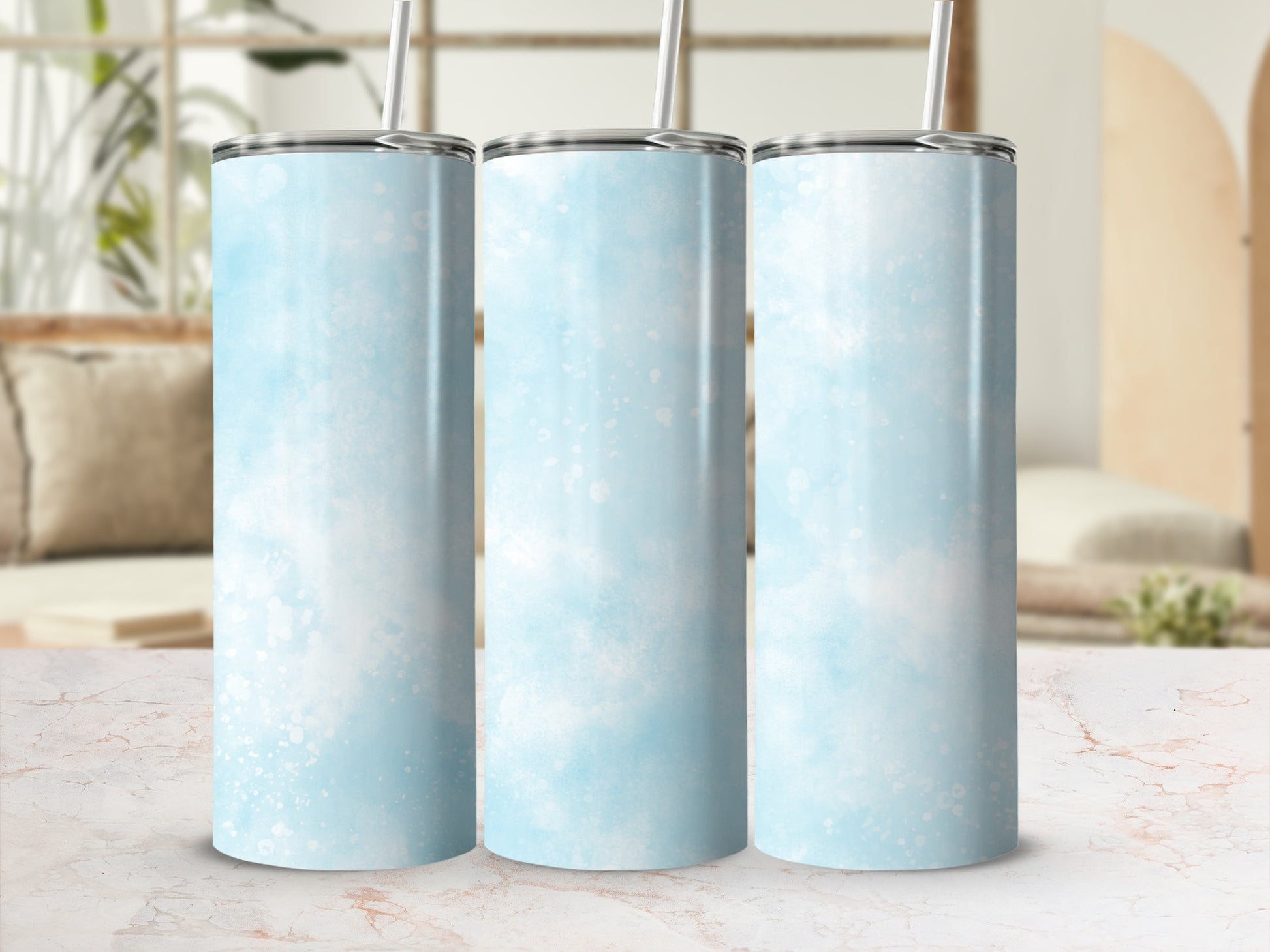 Three blue watercolor tumblers with straws on a marble surface.